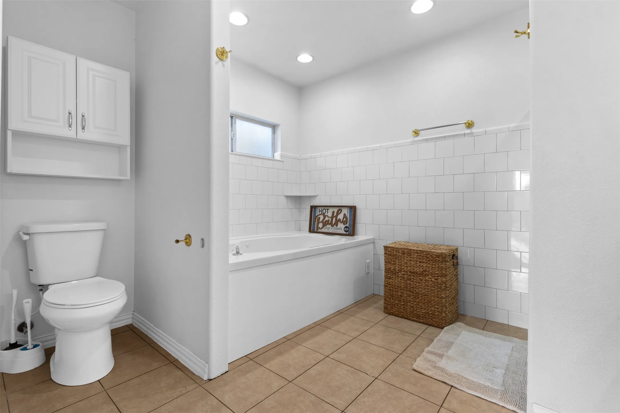 Bathroom featuring light tile patterned flooring, tile walls, a bath, and recessed lighting