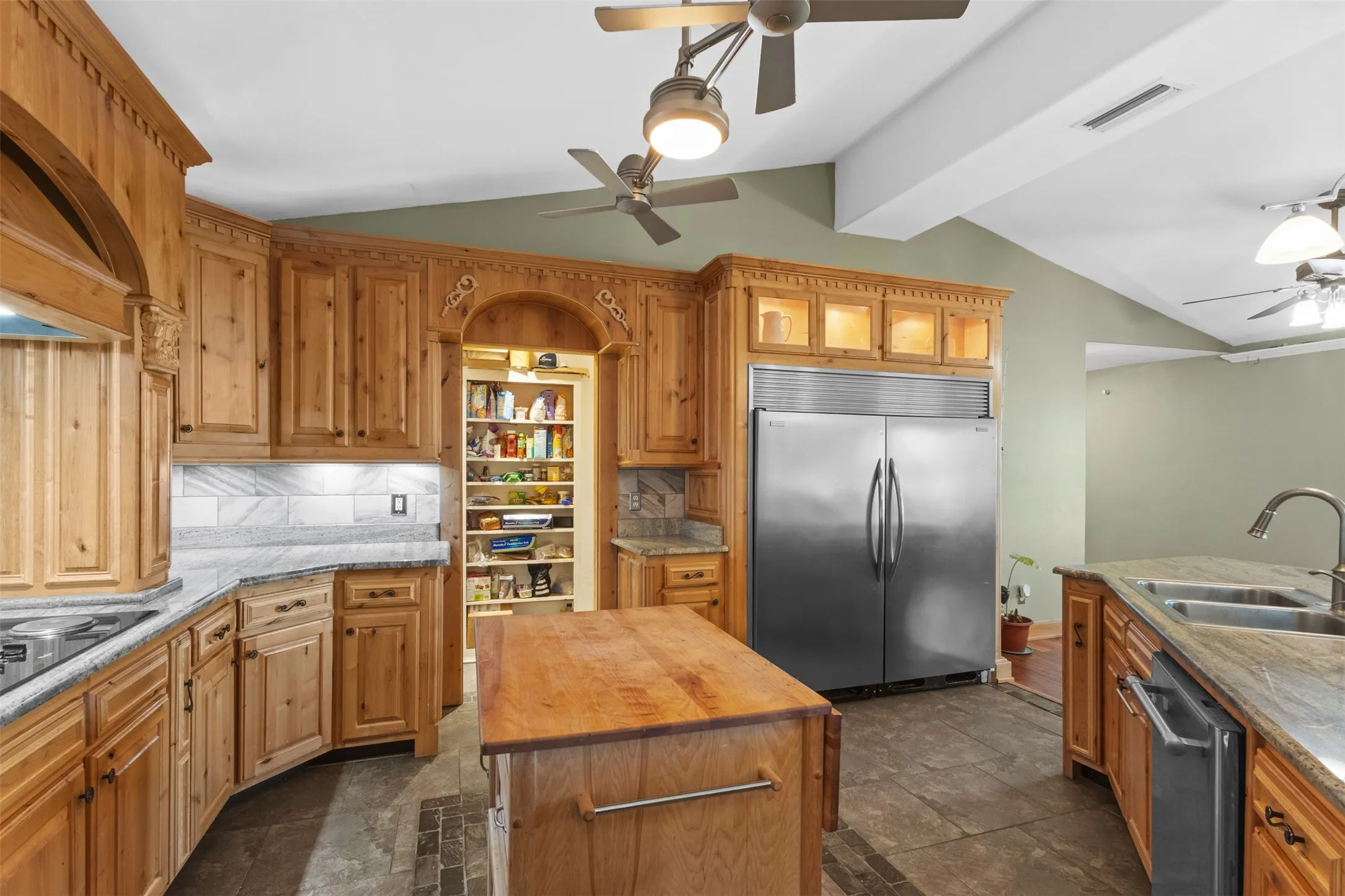 Kitchen with tasteful backsplash, appliances with stainless steel finishes, a ceiling fan, butcher block counters, and glass insert cabinets