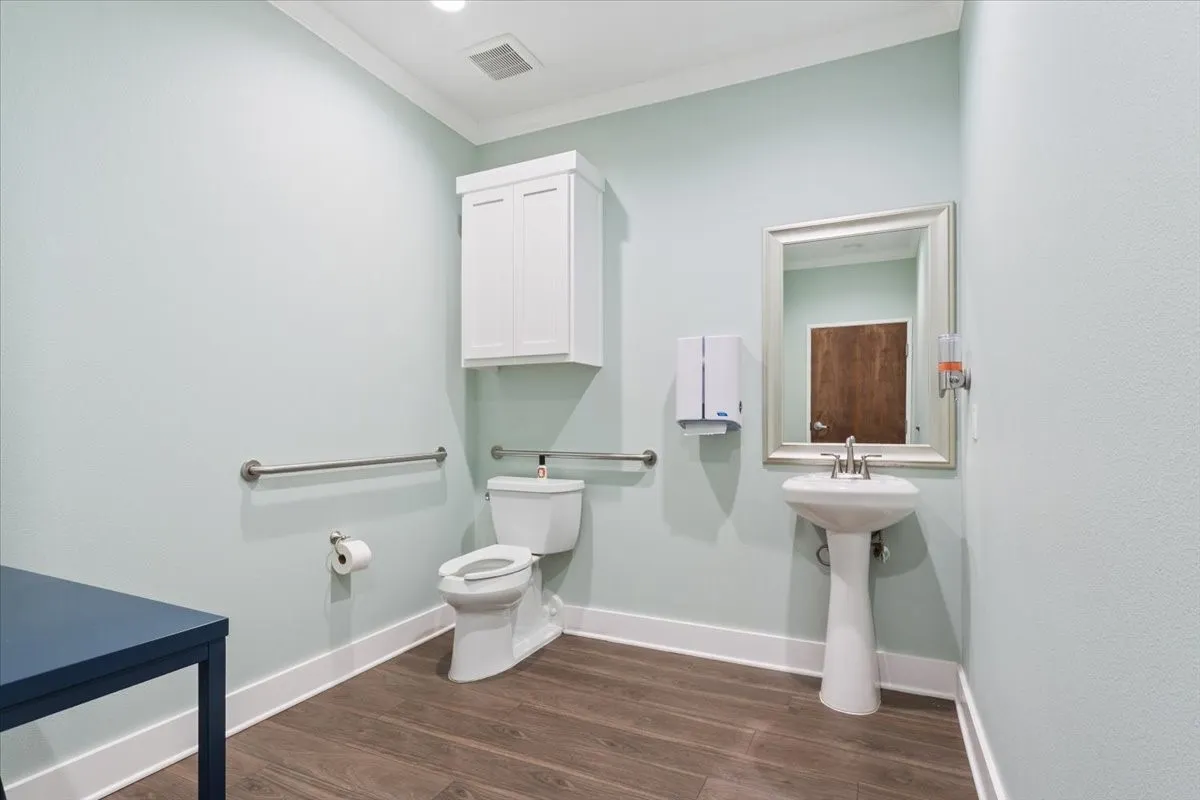 Bathroom featuring ornamental molding and dark wood finished floors