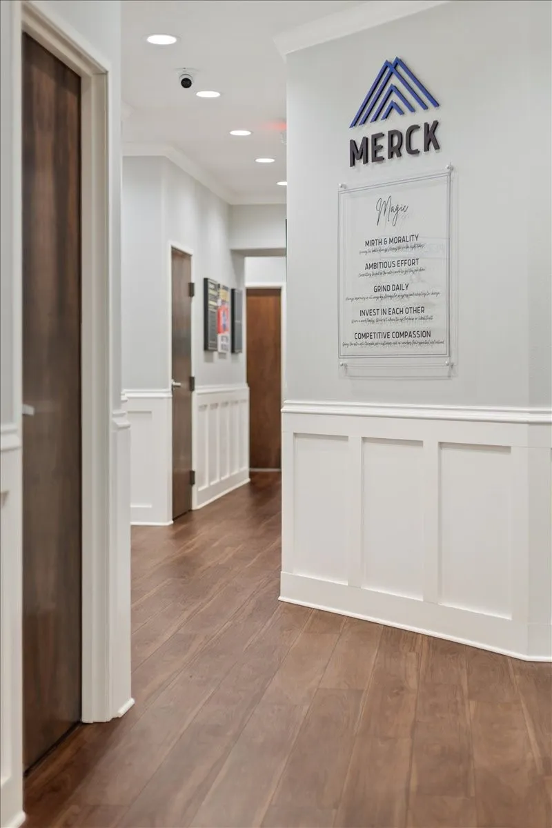 Corridor with dark wood-type flooring, crown molding, recessed lighting, a decorative wall, and wainscoting