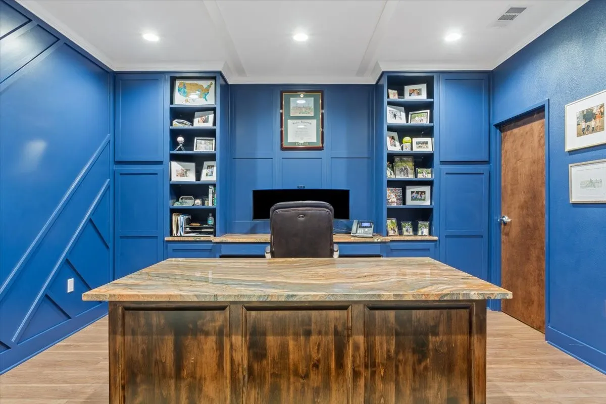 Office space with ornamental molding, light wood finished floors, built in desk, recessed lighting, and a decorative wall