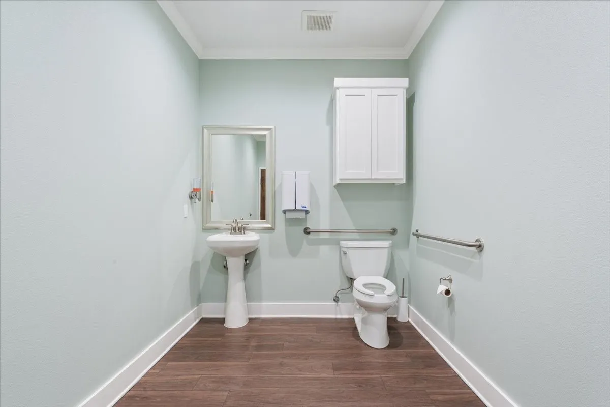 Half bath featuring dark wood finished floors and ornamental molding