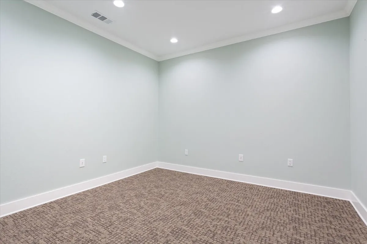 Carpeted empty room with crown molding and recessed lighting