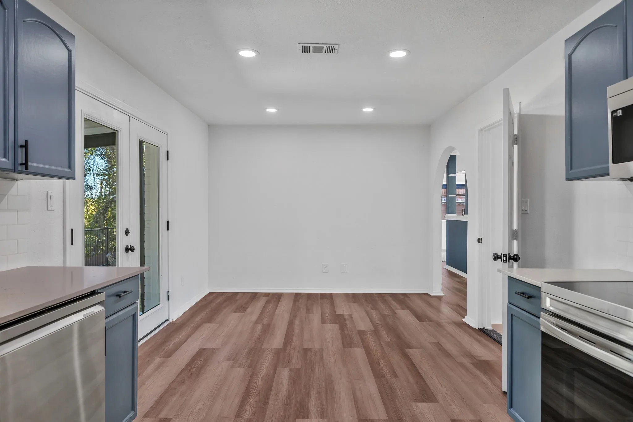 Kitchen with blue cabinetry, stainless steel appliances, light wood finished floors, light stone counters, and recessed lighting
