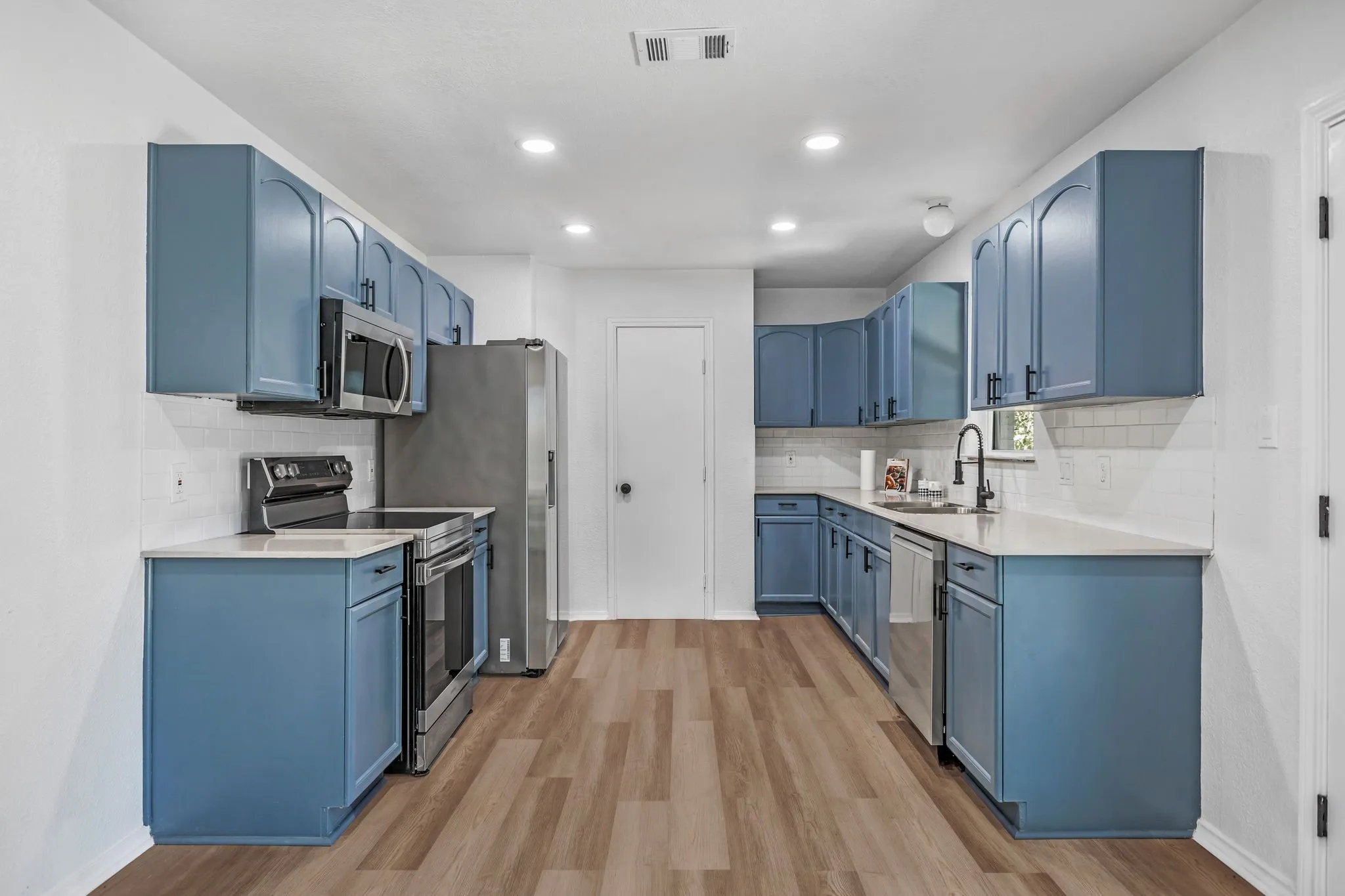 Kitchen featuring blue cabinets, appliances with stainless steel finishes, tasteful backsplash, and recessed lighting