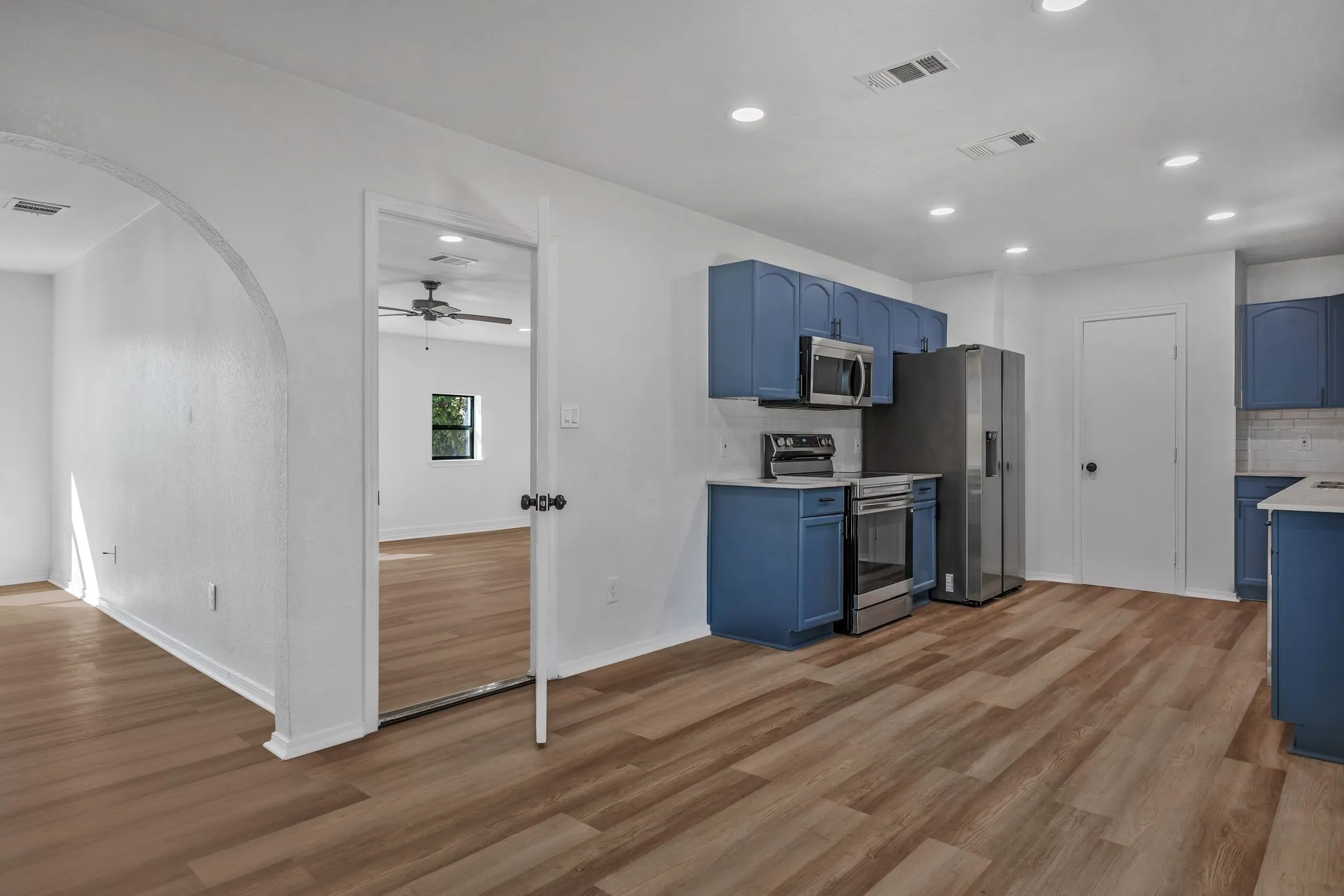 Kitchen featuring blue cabinets, decorative backsplash, appliances with stainless steel finishes, light wood-style floors, and recessed lighting