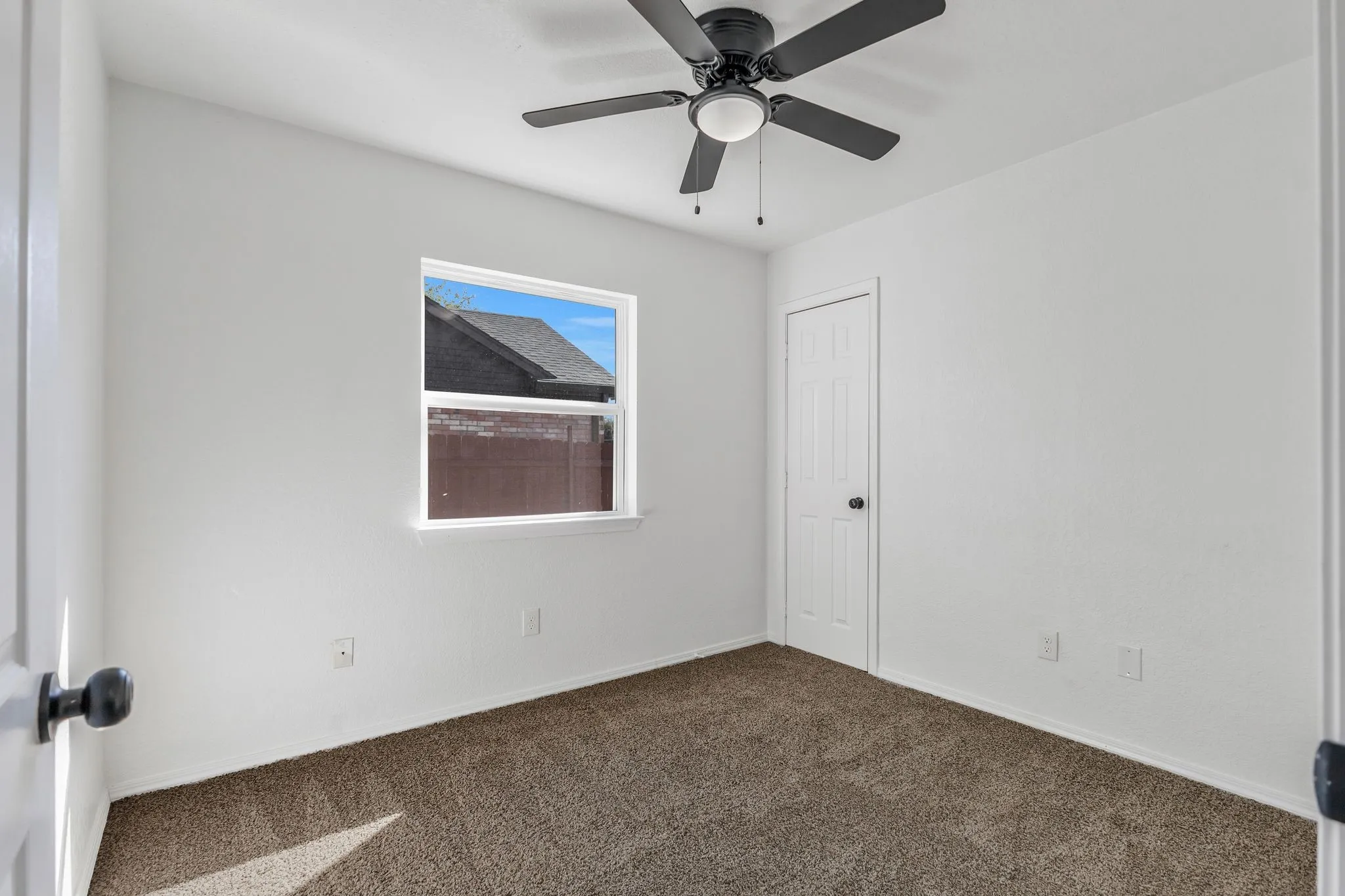 Spare room featuring dark colored carpet and ceiling fan