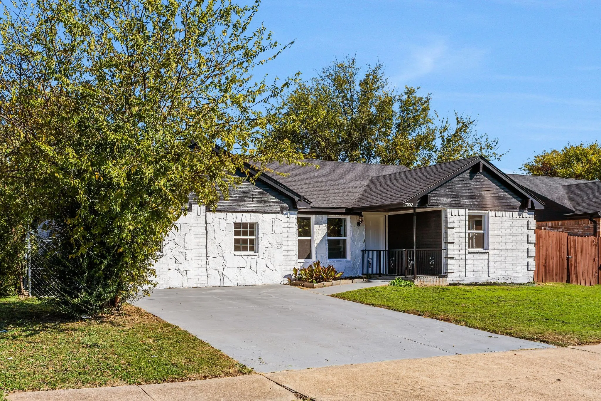 Ranch-style home featuring covered porch and stone siding