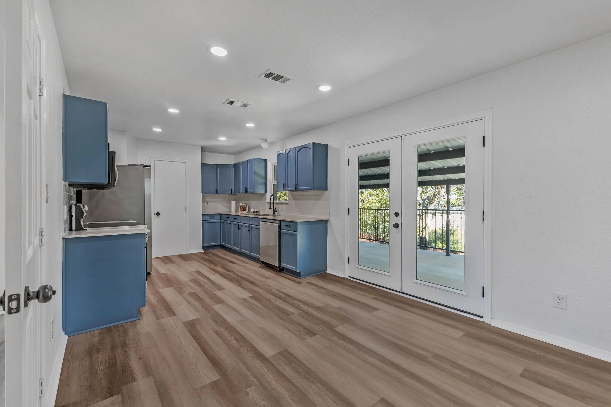 Kitchen featuring blue cabinets, french doors, backsplash, recessed lighting, and light wood-style flooring
