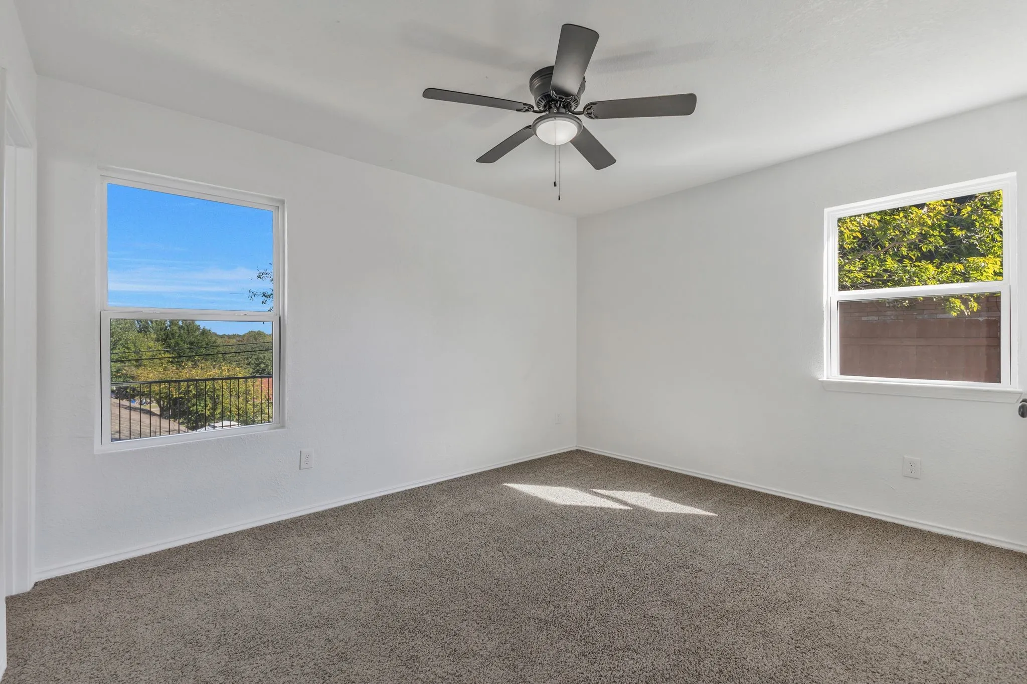 Carpeted empty room with baseboards and a ceiling fan