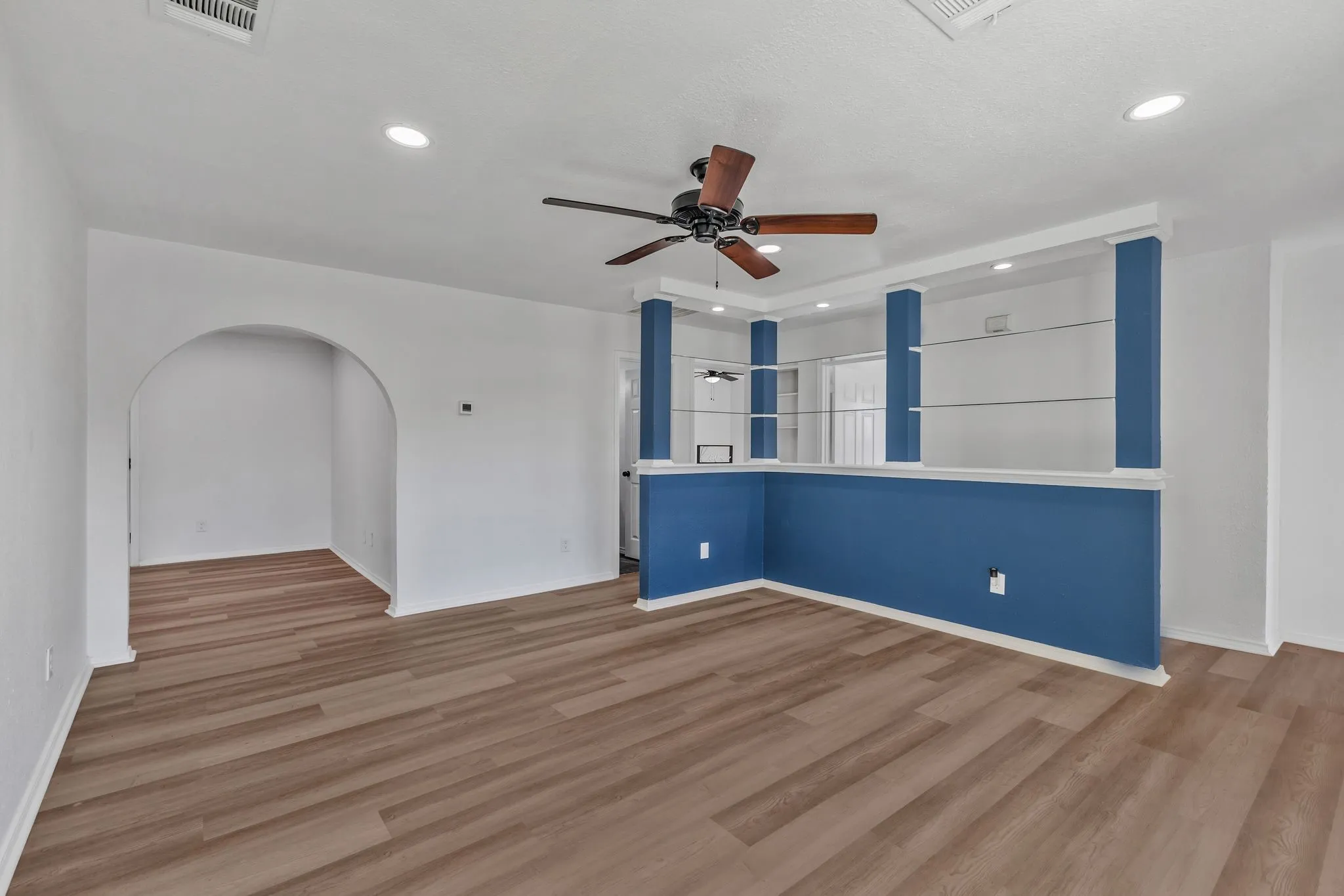Spare room featuring a ceiling fan, wood finished floors, arched walkways, and recessed lighting
