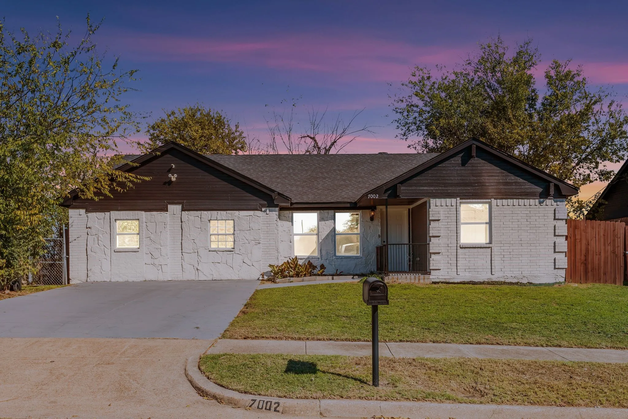 Ranch-style home with driveway, a porch, and roof with shingles