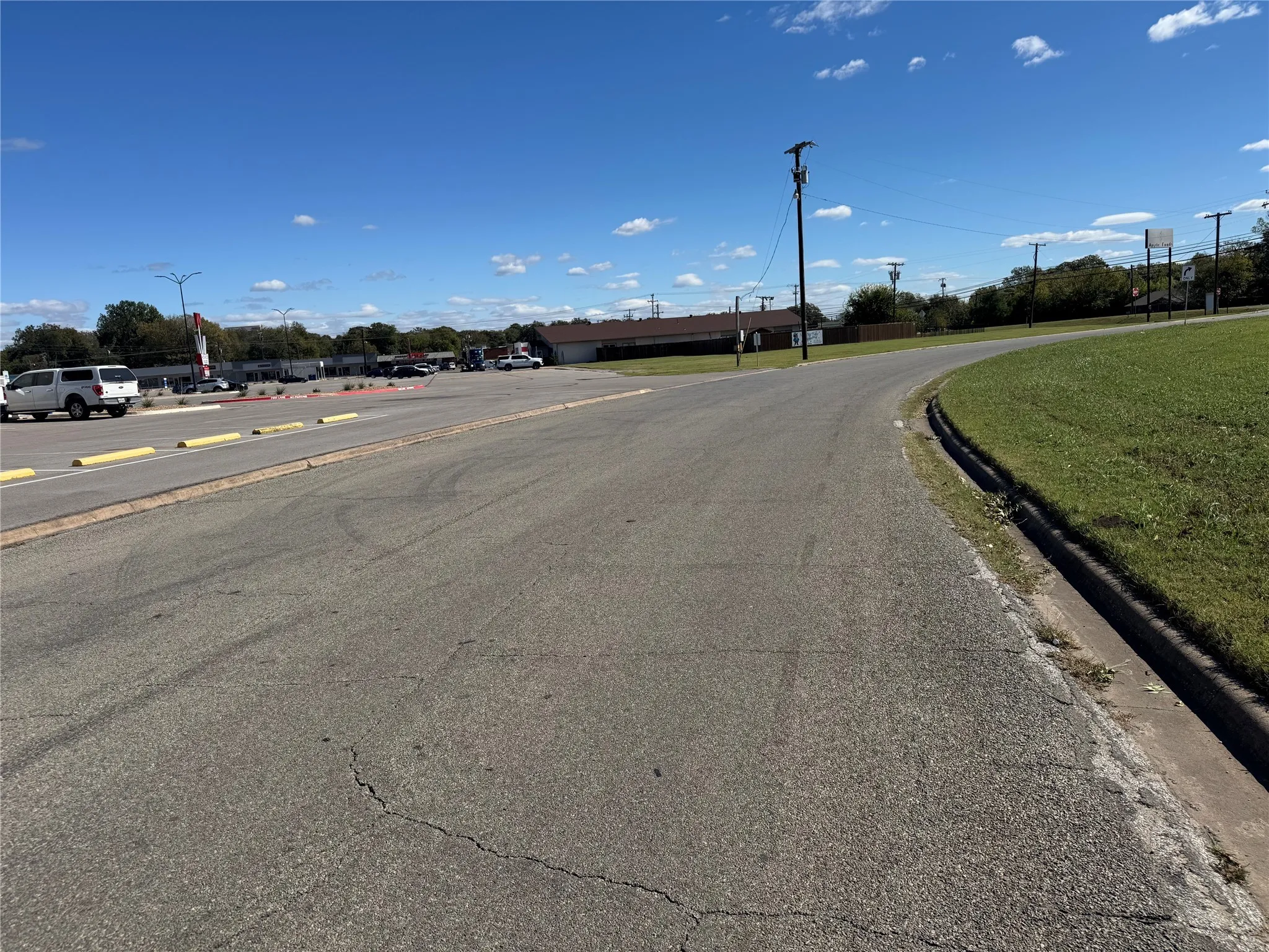 View of asphalt road featuring curbs and street lighting