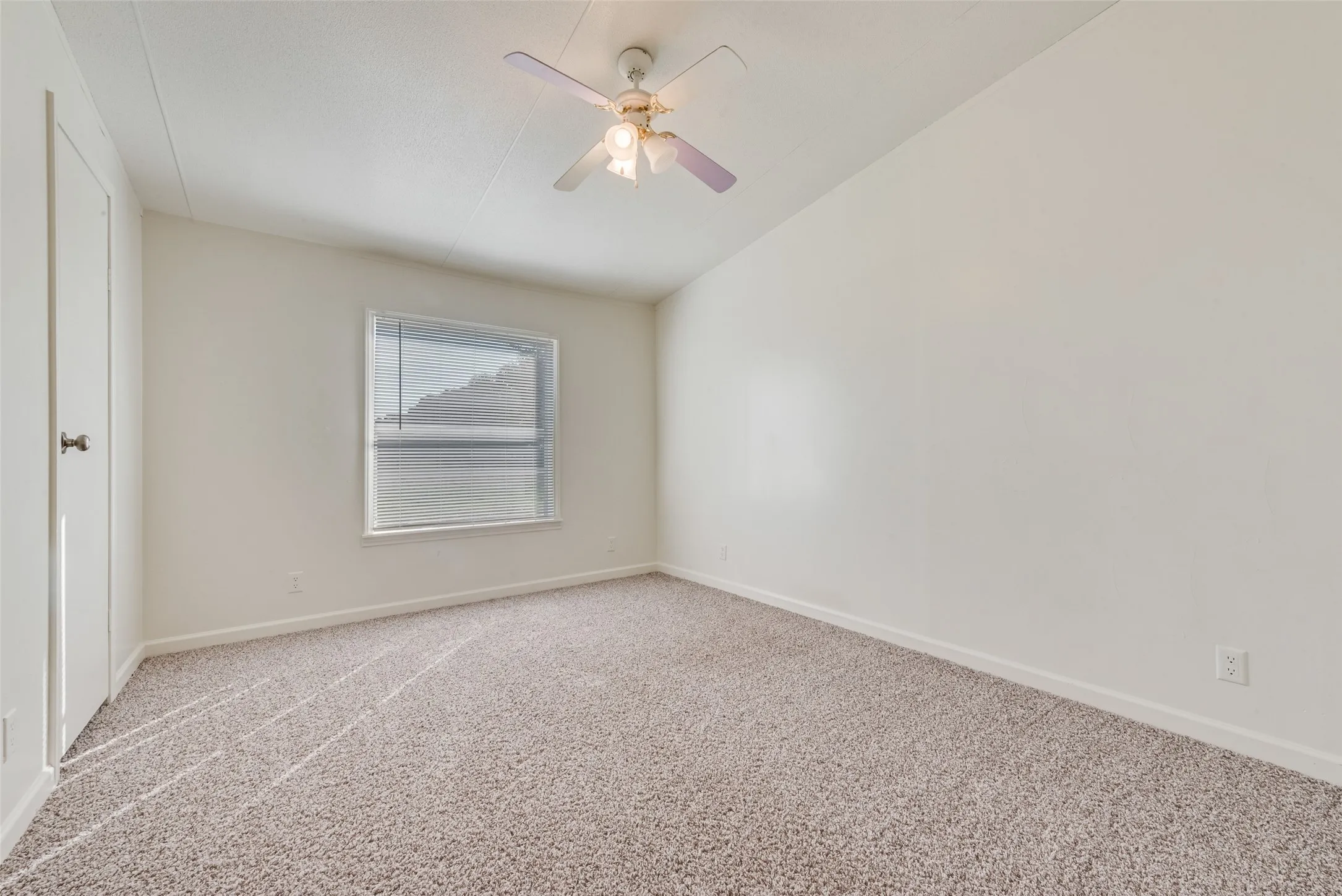Carpeted spare room featuring baseboards and a ceiling fan