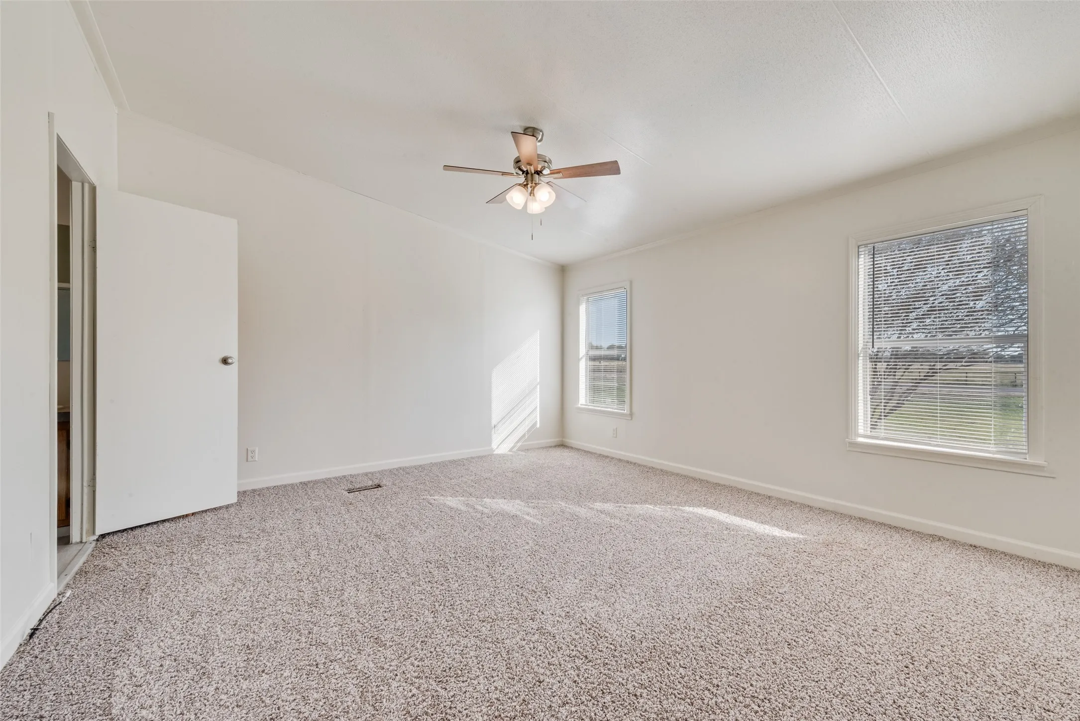 Carpeted empty room featuring baseboards and a ceiling fan