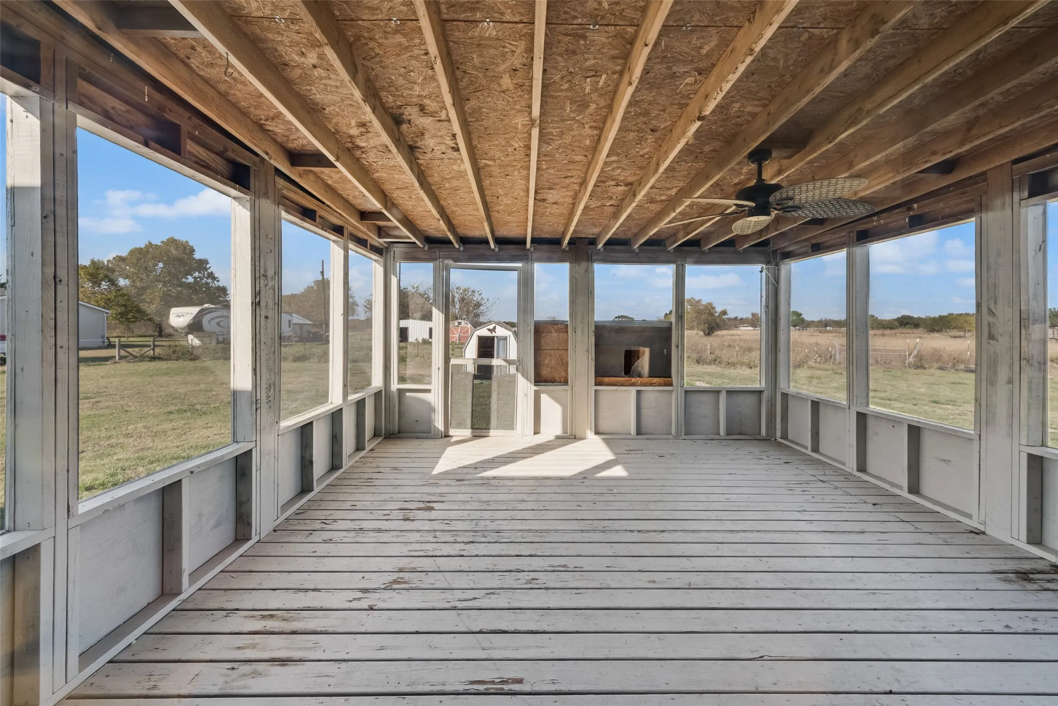 Unfurnished sunroom with a wooden deck and ceiling fan