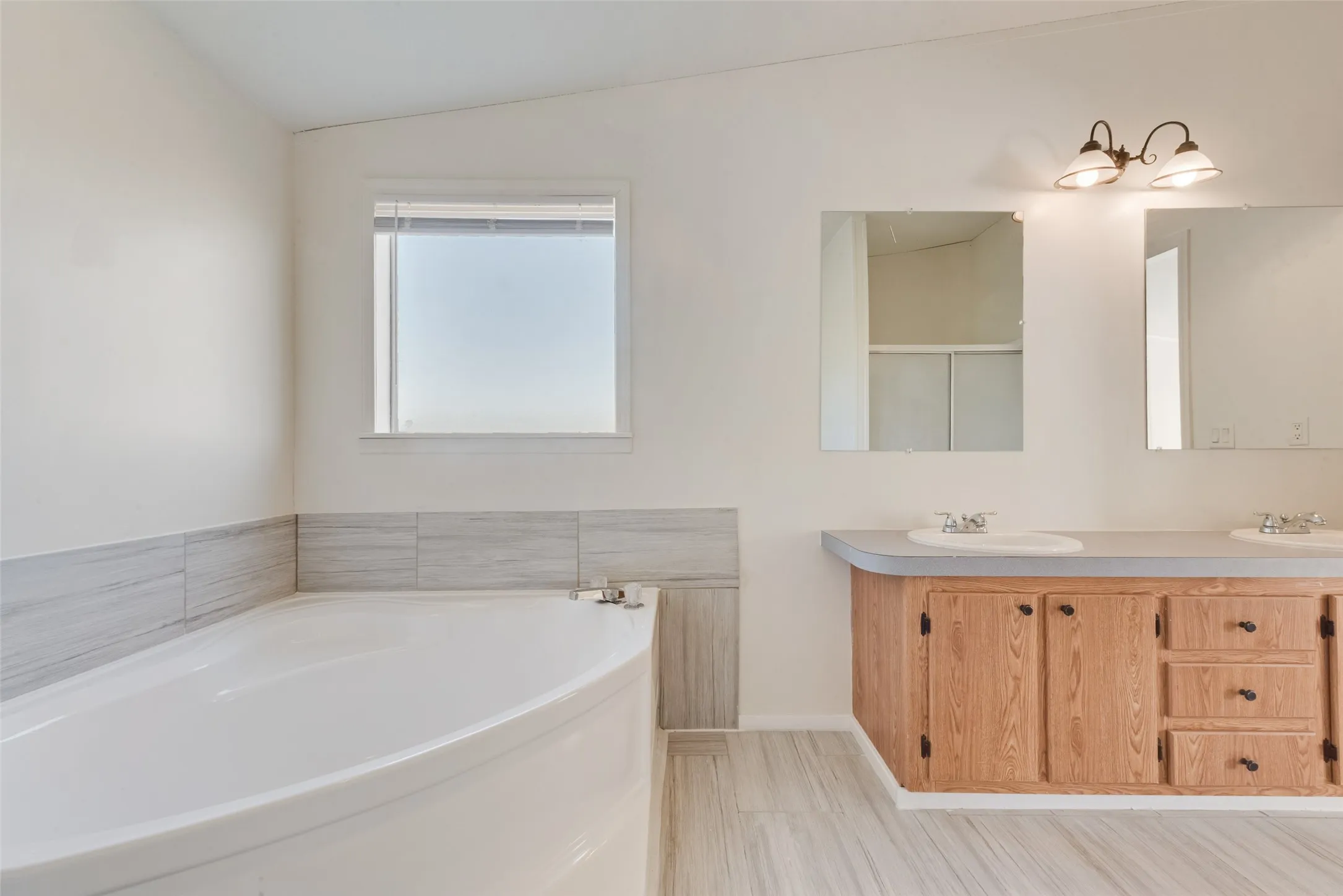 Full bathroom featuring double vanity, a bath, vaulted ceiling, and a shower stall