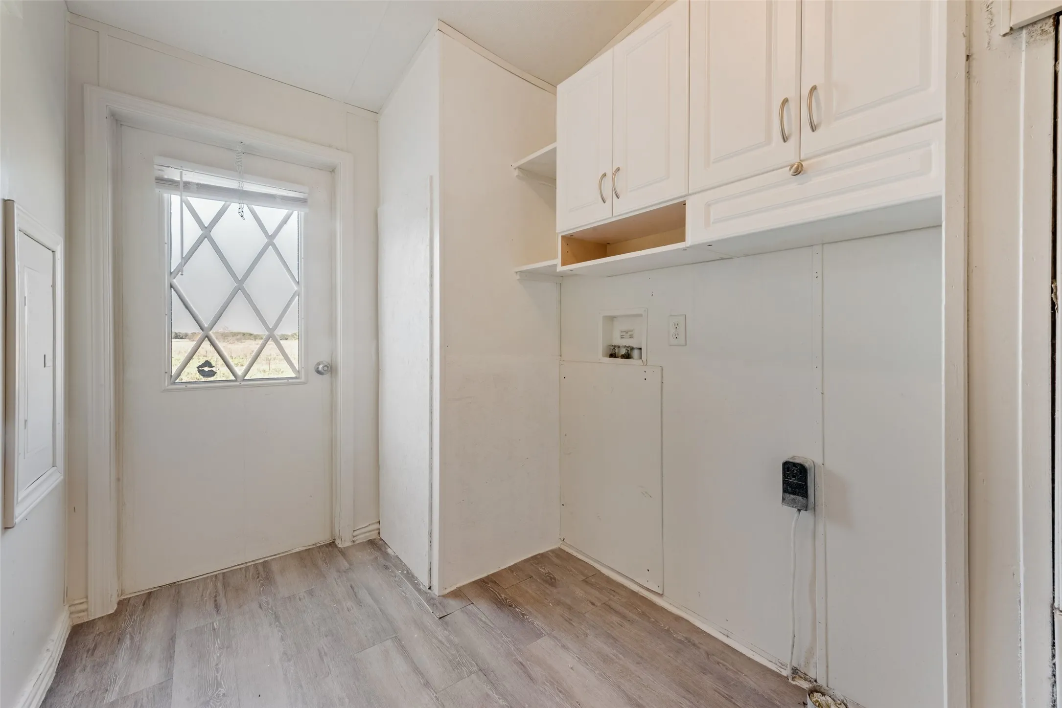 Laundry room with light wood-style flooring, cabinet space, and washer hookup