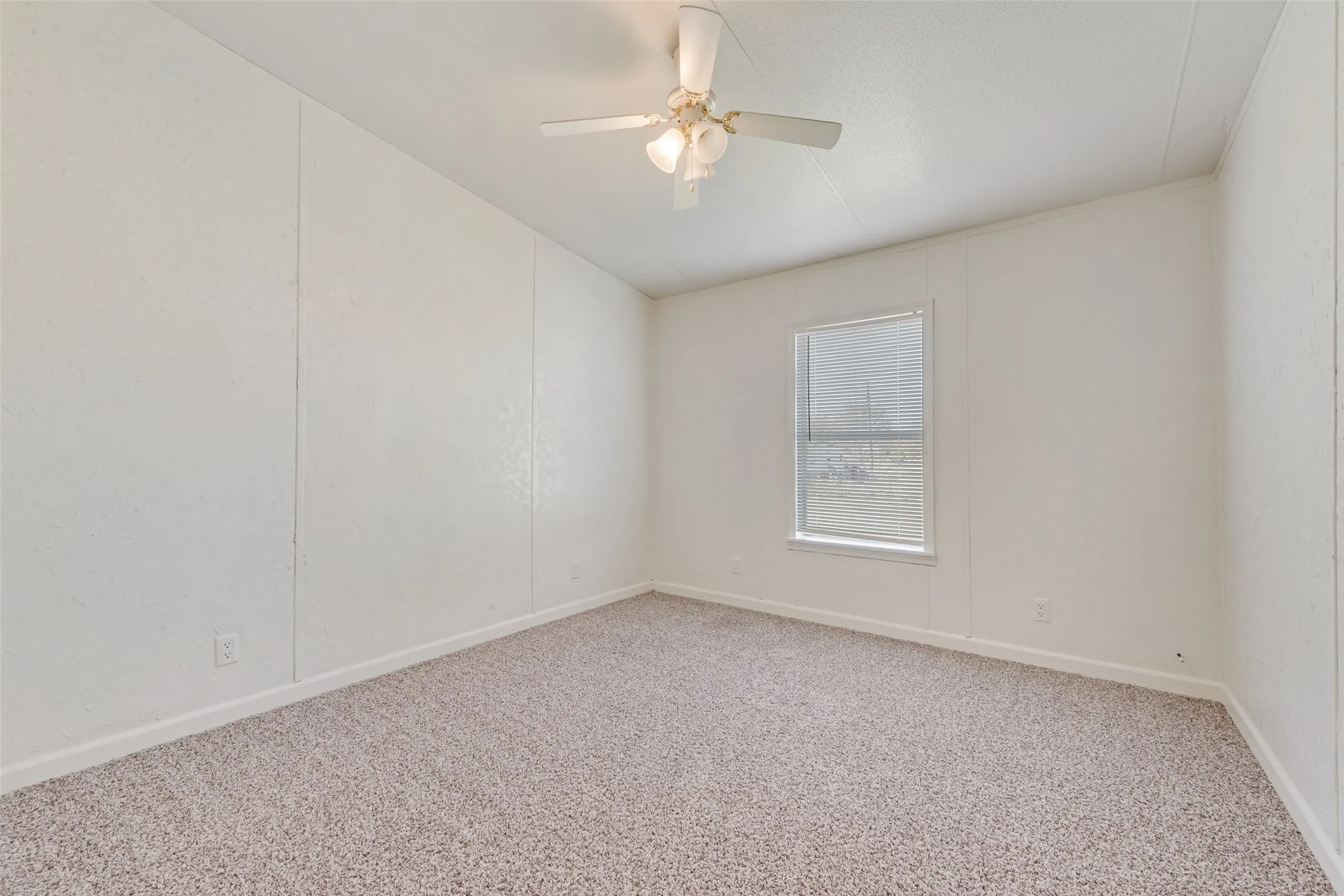 Carpeted empty room with baseboards and a ceiling fan