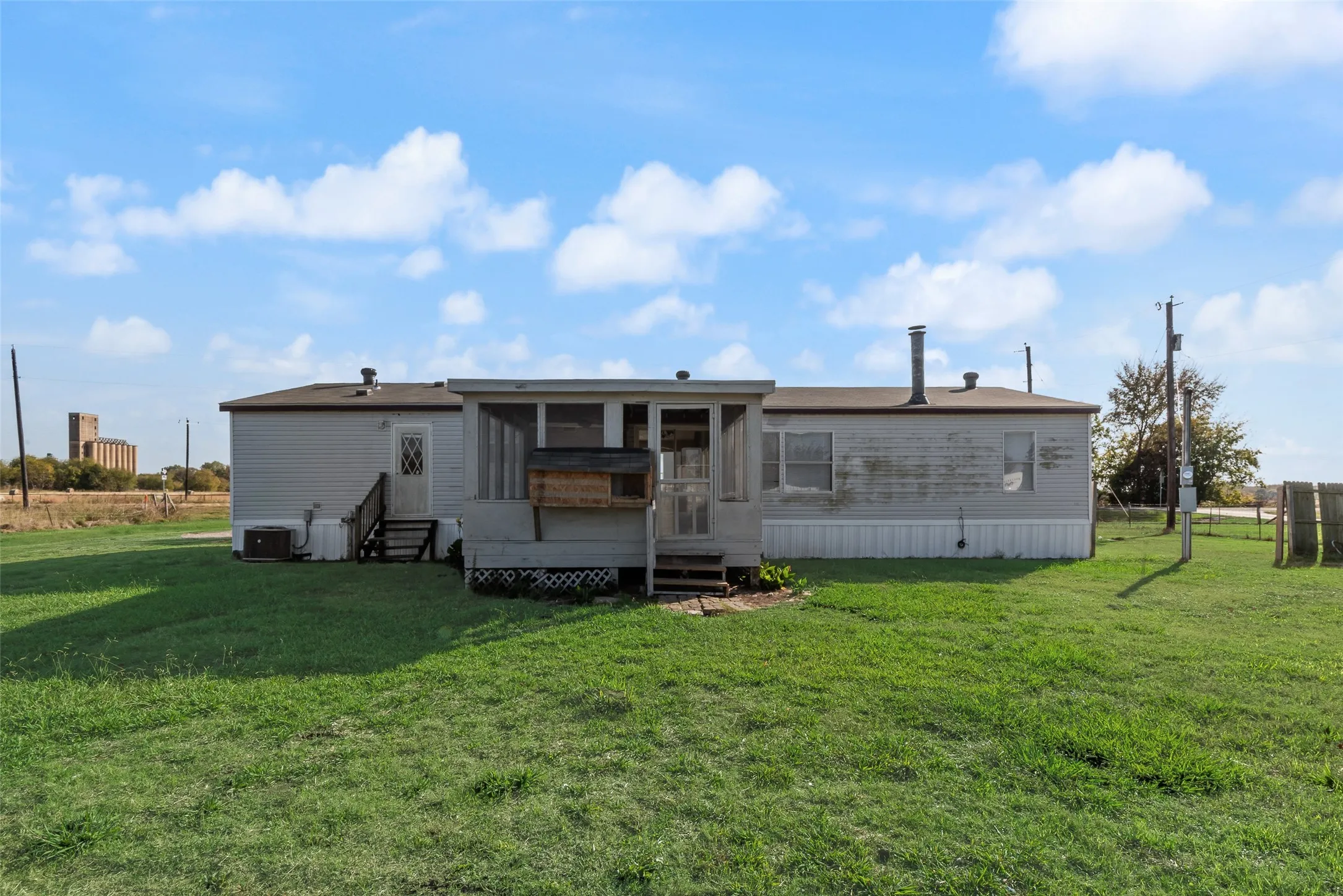 Rear view of house featuring a sunroom, a lawn, and entry steps
