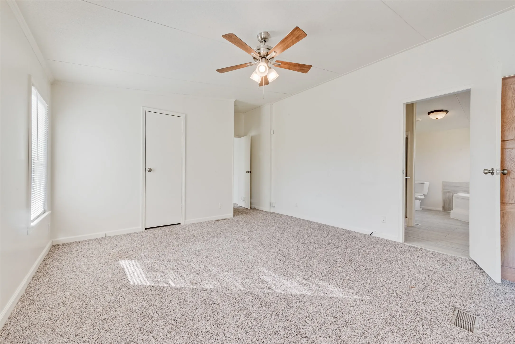 Unfurnished bedroom with light carpet and a ceiling fan
