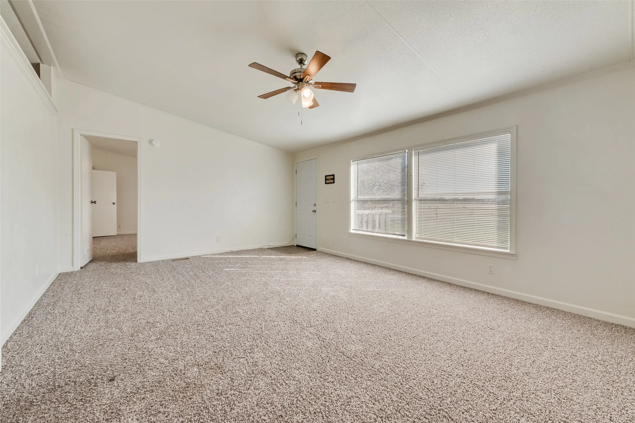 Carpeted spare room with baseboards and ceiling fan