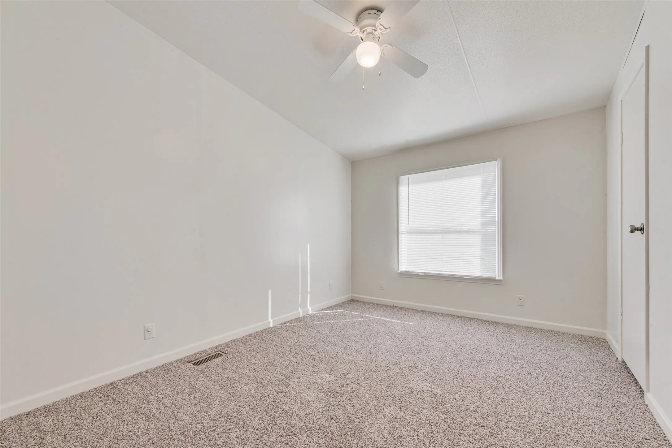 Carpeted empty room with baseboards and a ceiling fan