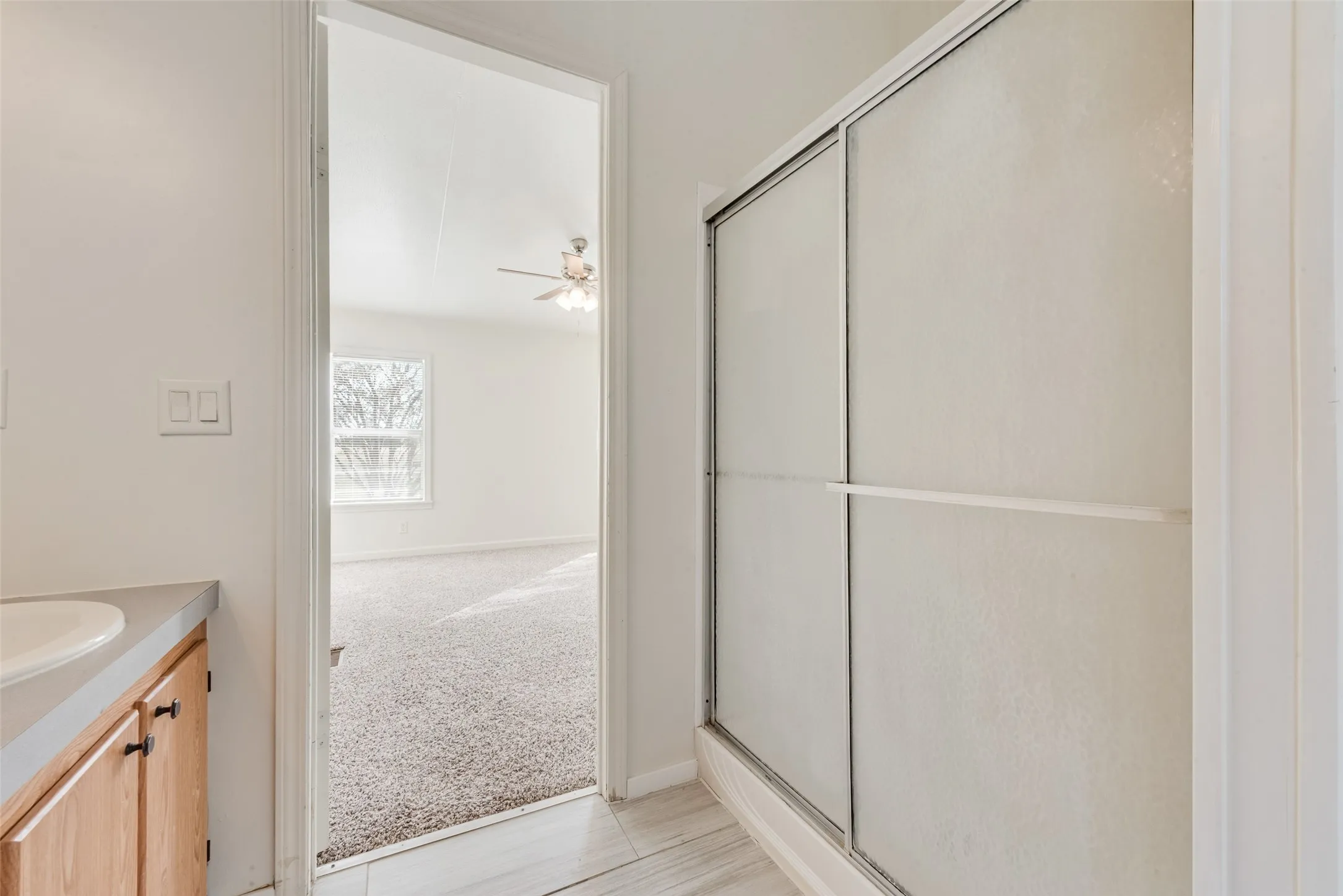 Full bathroom featuring vanity, light colored carpet, a stall shower, and ceiling fan