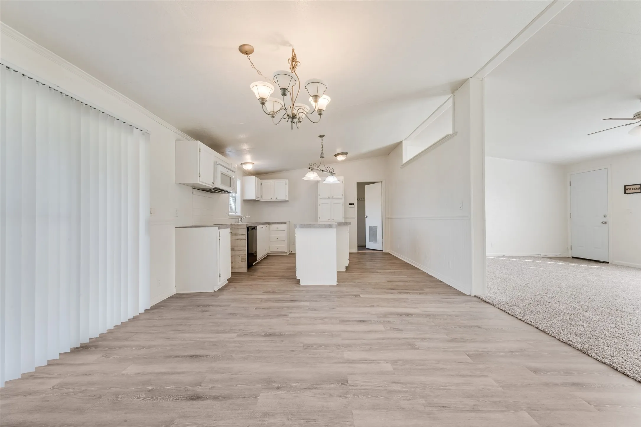 Kitchen with open floor plan, white cabinetry, pendant lighting, a center island, and a chandelier