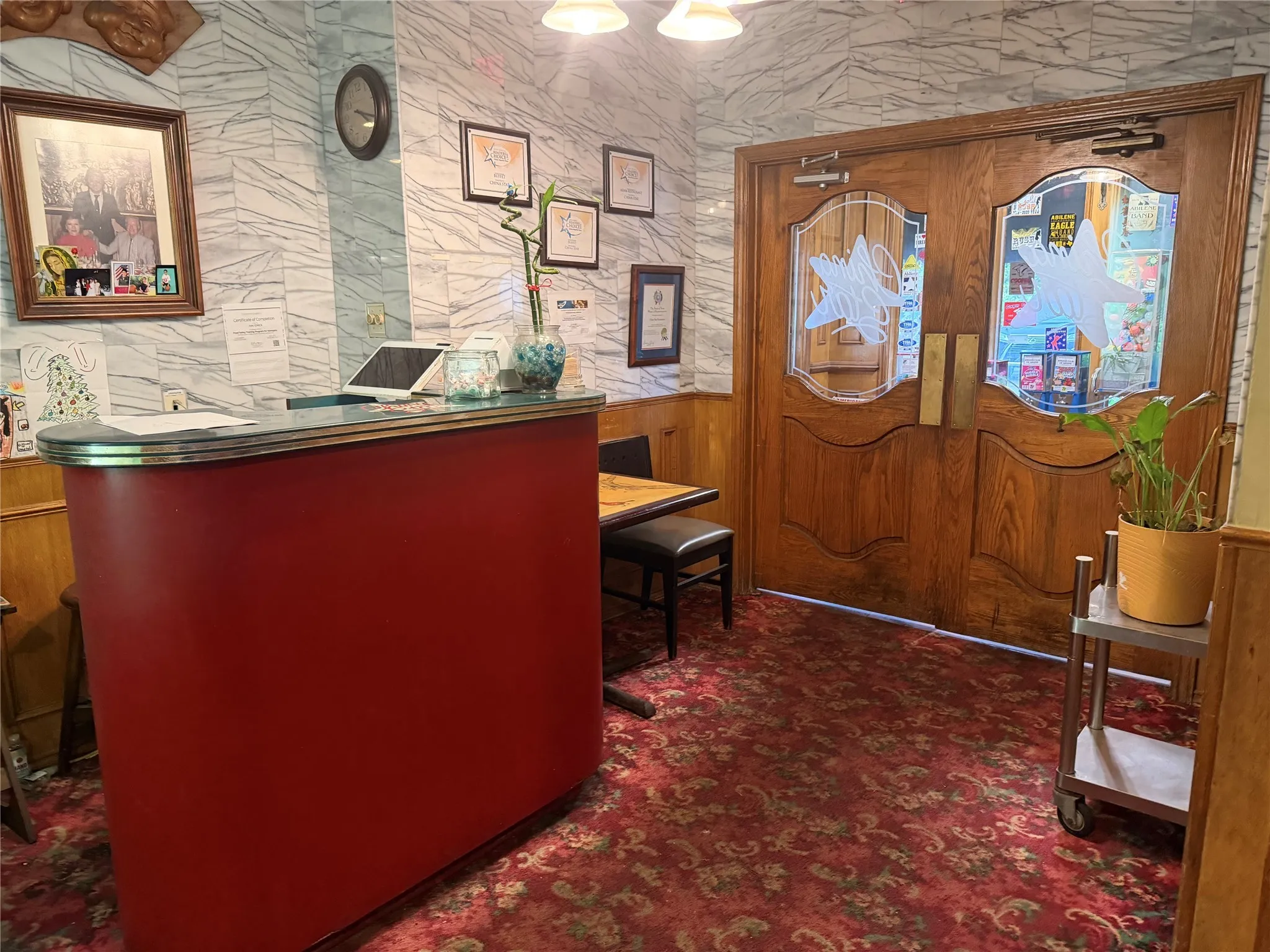 Foyer featuring dark carpet, wainscoting, and wooden walls