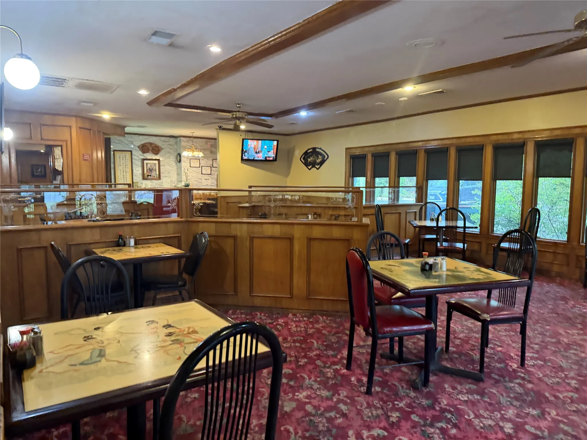 Dining room featuring a ceiling fan, dark carpet, wooden walls, and ornamental molding