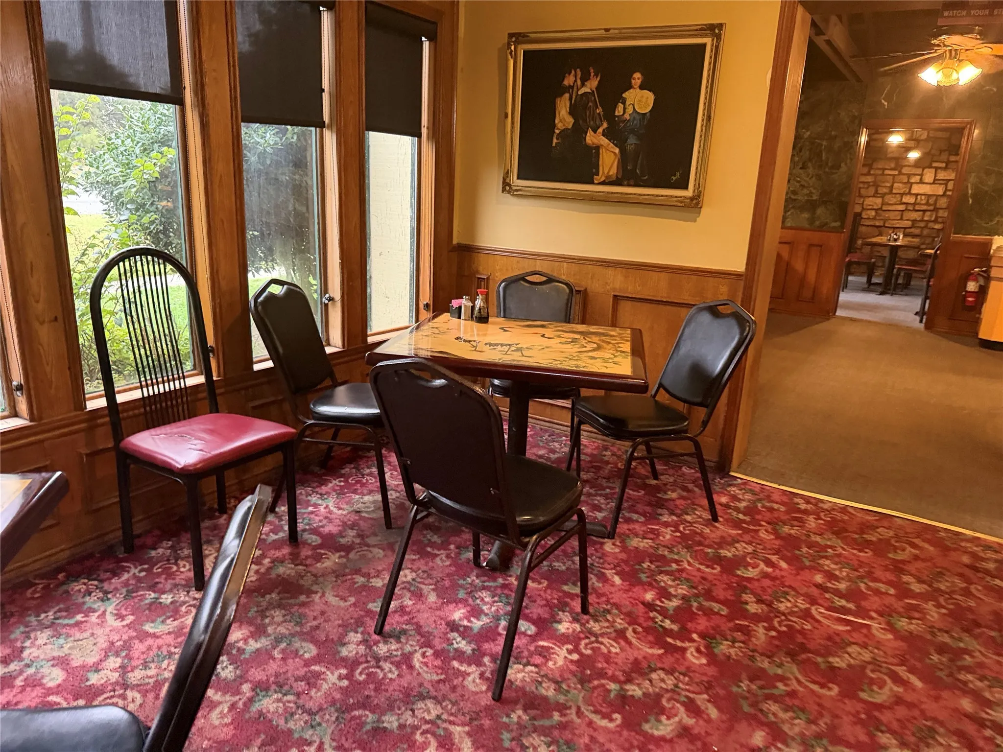 Carpeted dining area featuring wainscoting, wood walls, and ceiling fan
