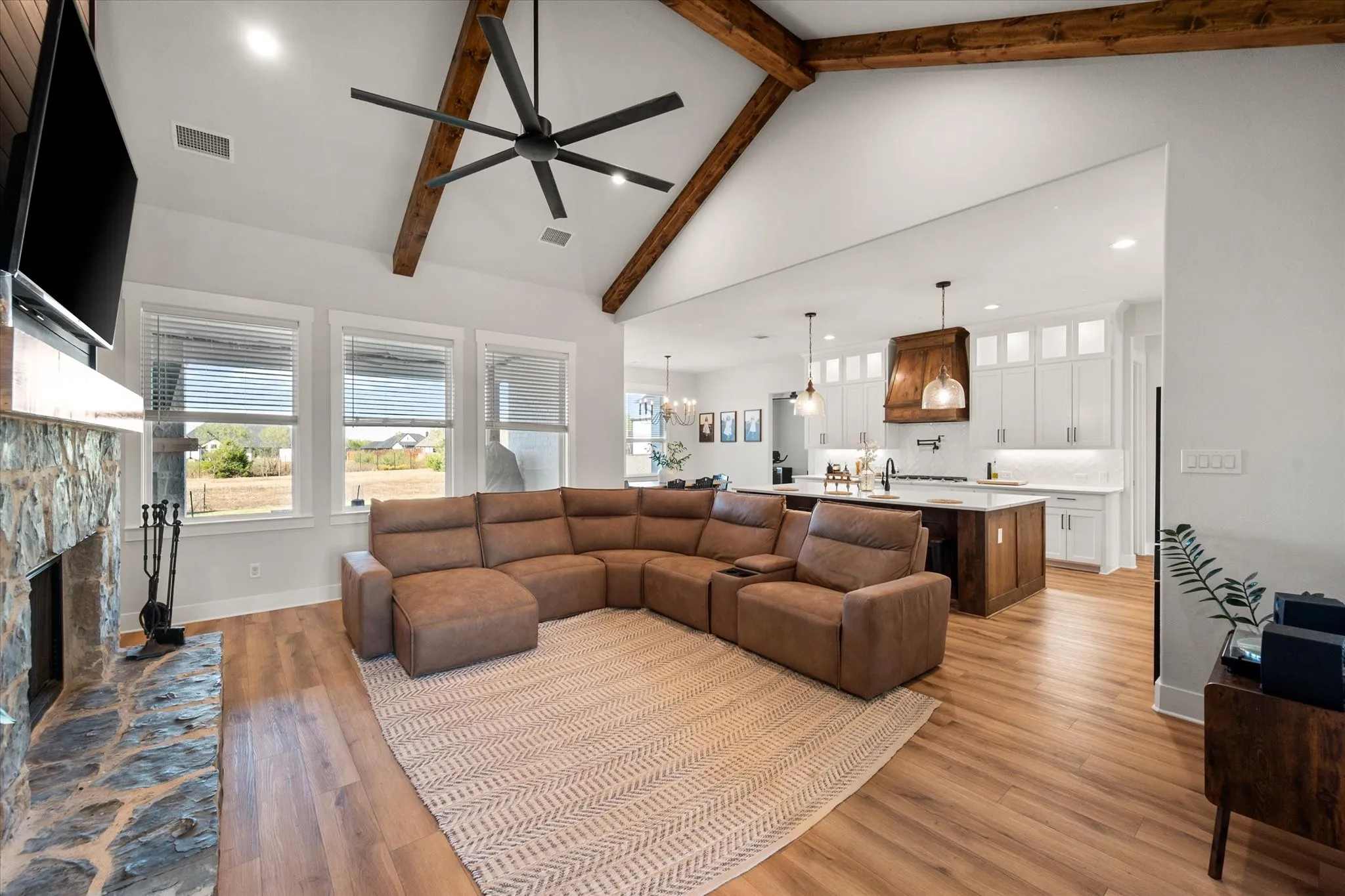 Living area featuring light wood finished floors, high vaulted ceiling, a fireplace, beamed ceiling, and recessed lighting