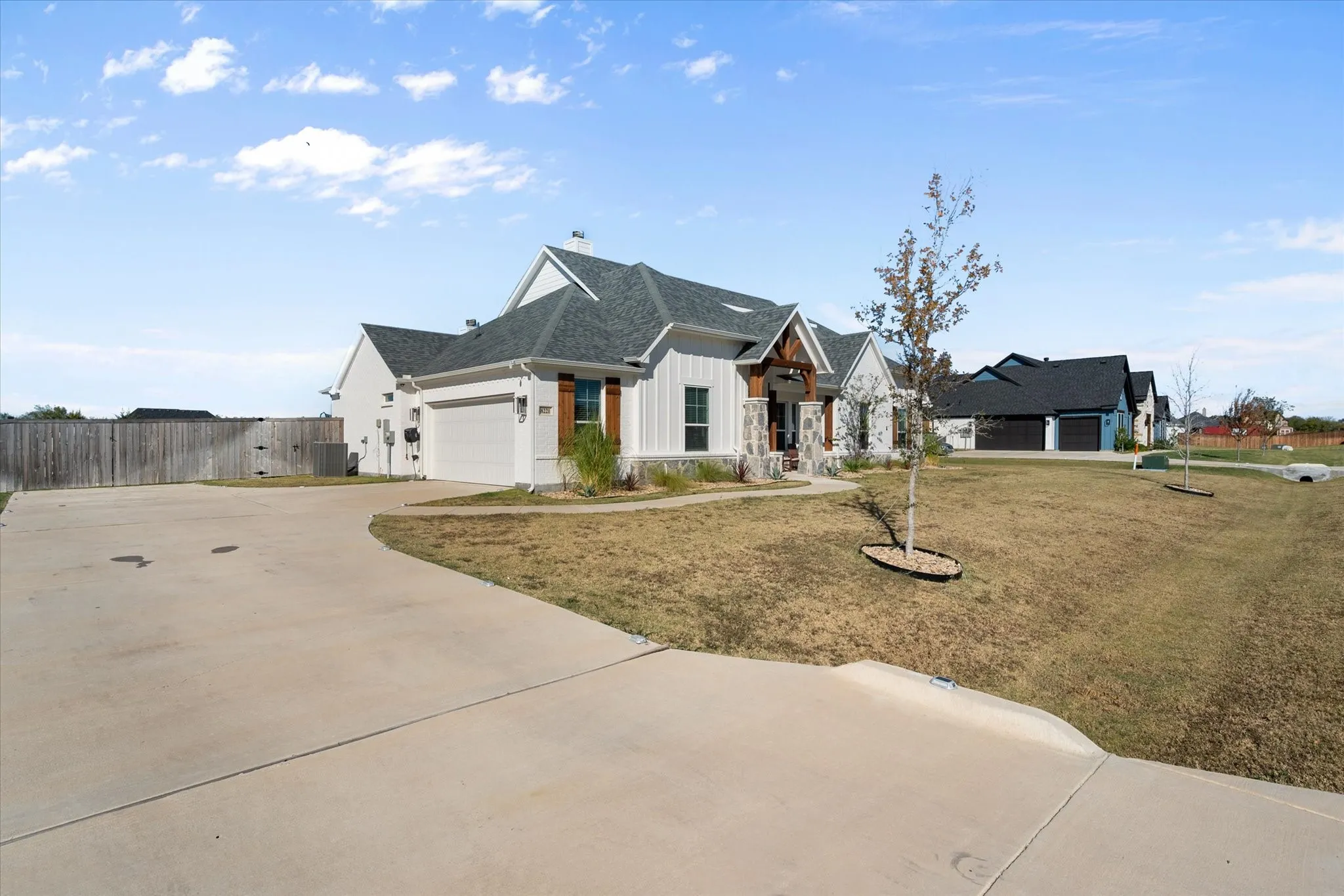 Modern farmhouse featuring board and batten siding, driveway, a chimney, a garage, and a shingled roof