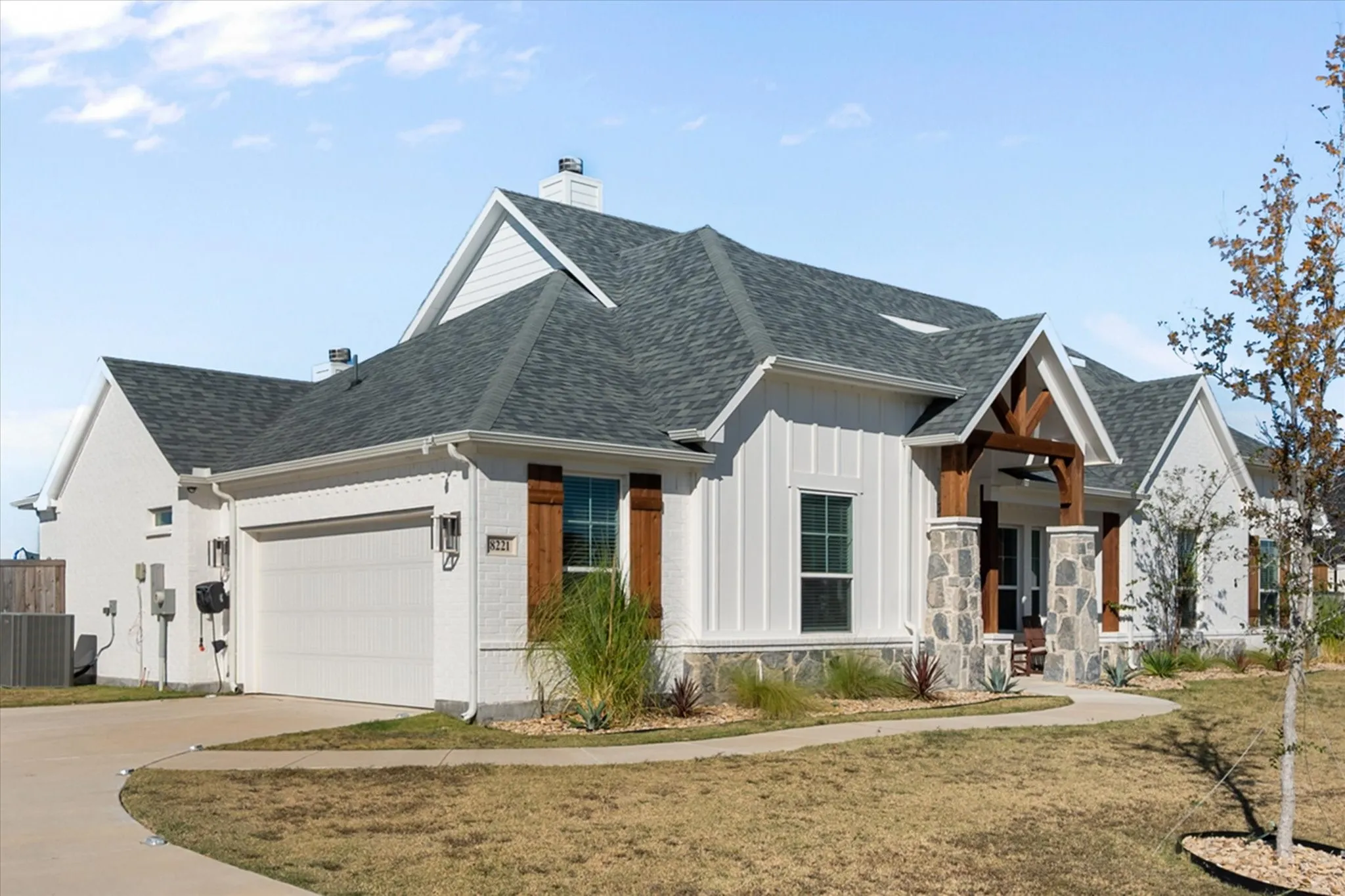 View of front of property featuring a chimney, driveway, a garage, and roof with shingles