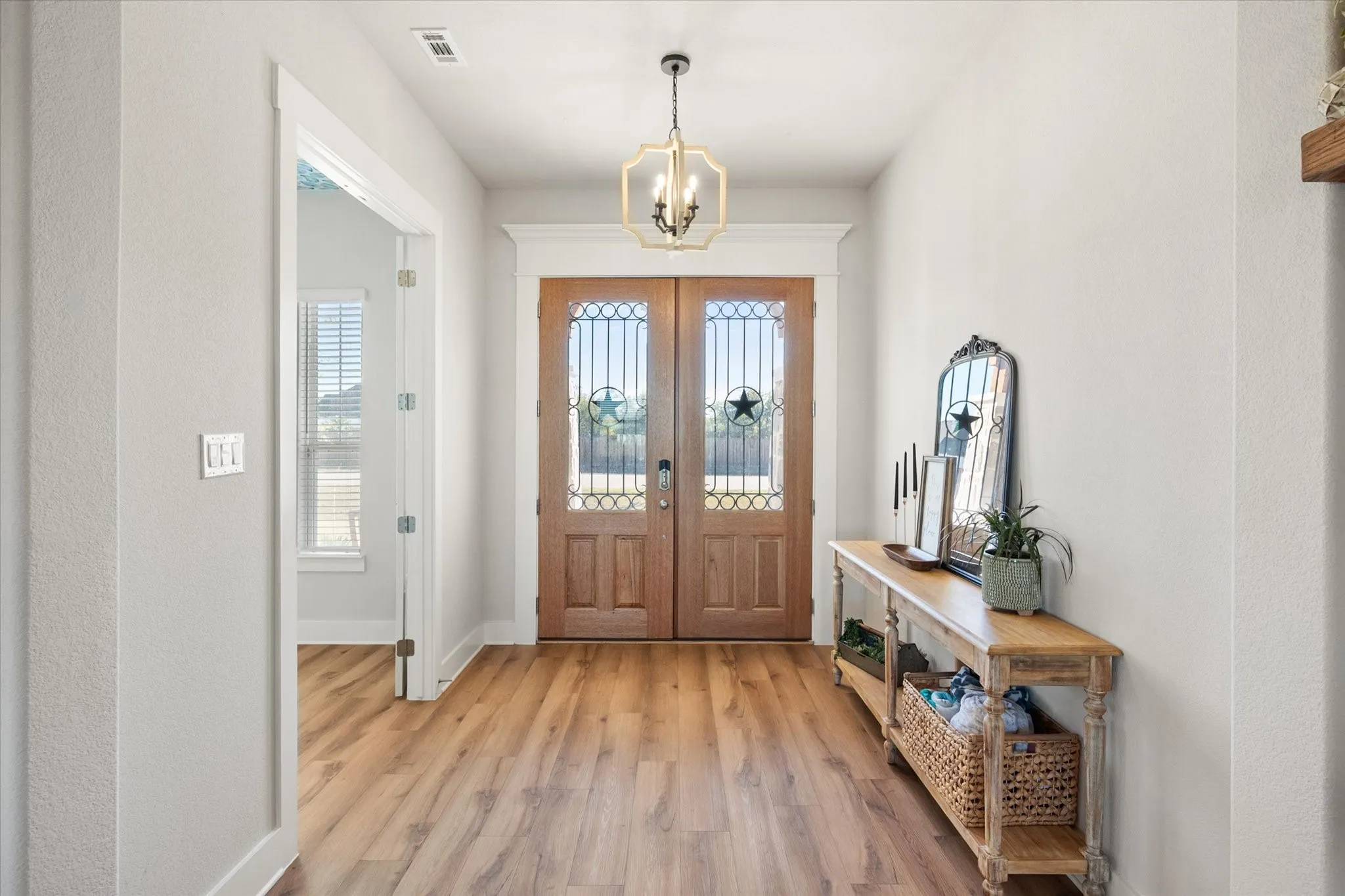 Foyer entrance with light wood-style floors, a chandelier, and a textured wall