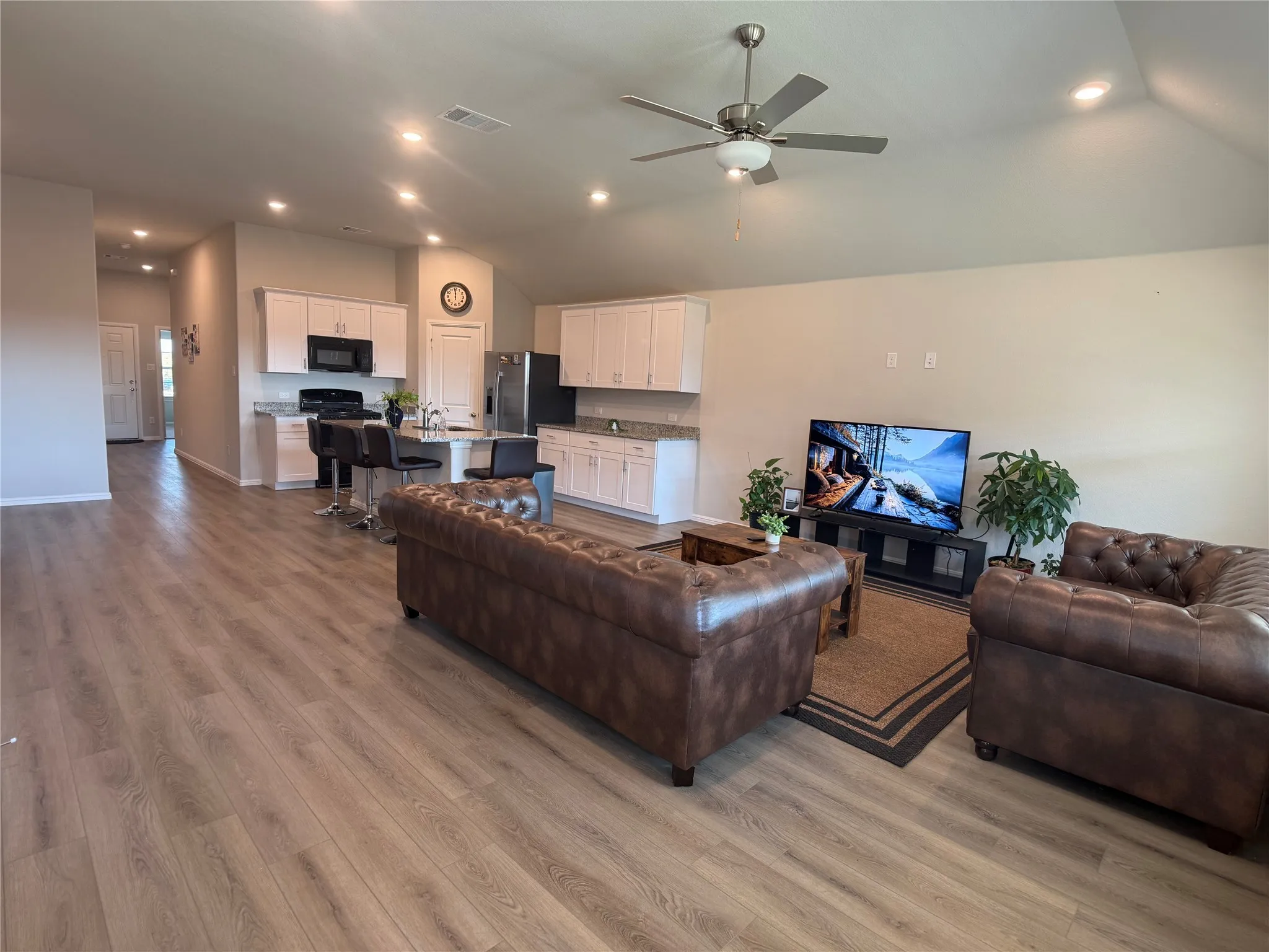 Living area with recessed lighting, light wood-style flooring, ceiling fan, and lofted ceiling
