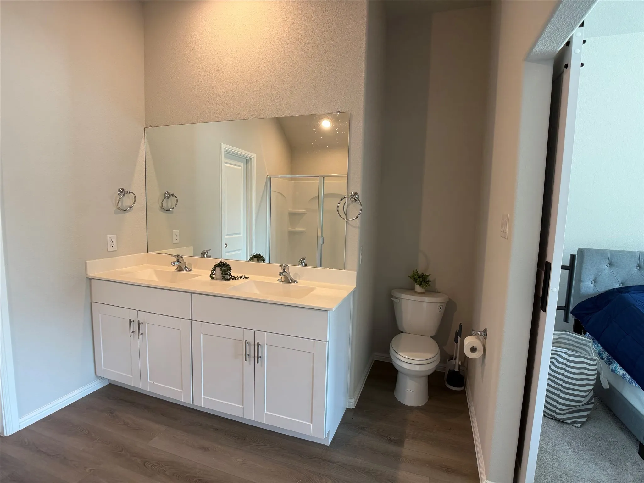 Bathroom with double vanity, dark wood finished floors, a stall shower, and connected bathroom