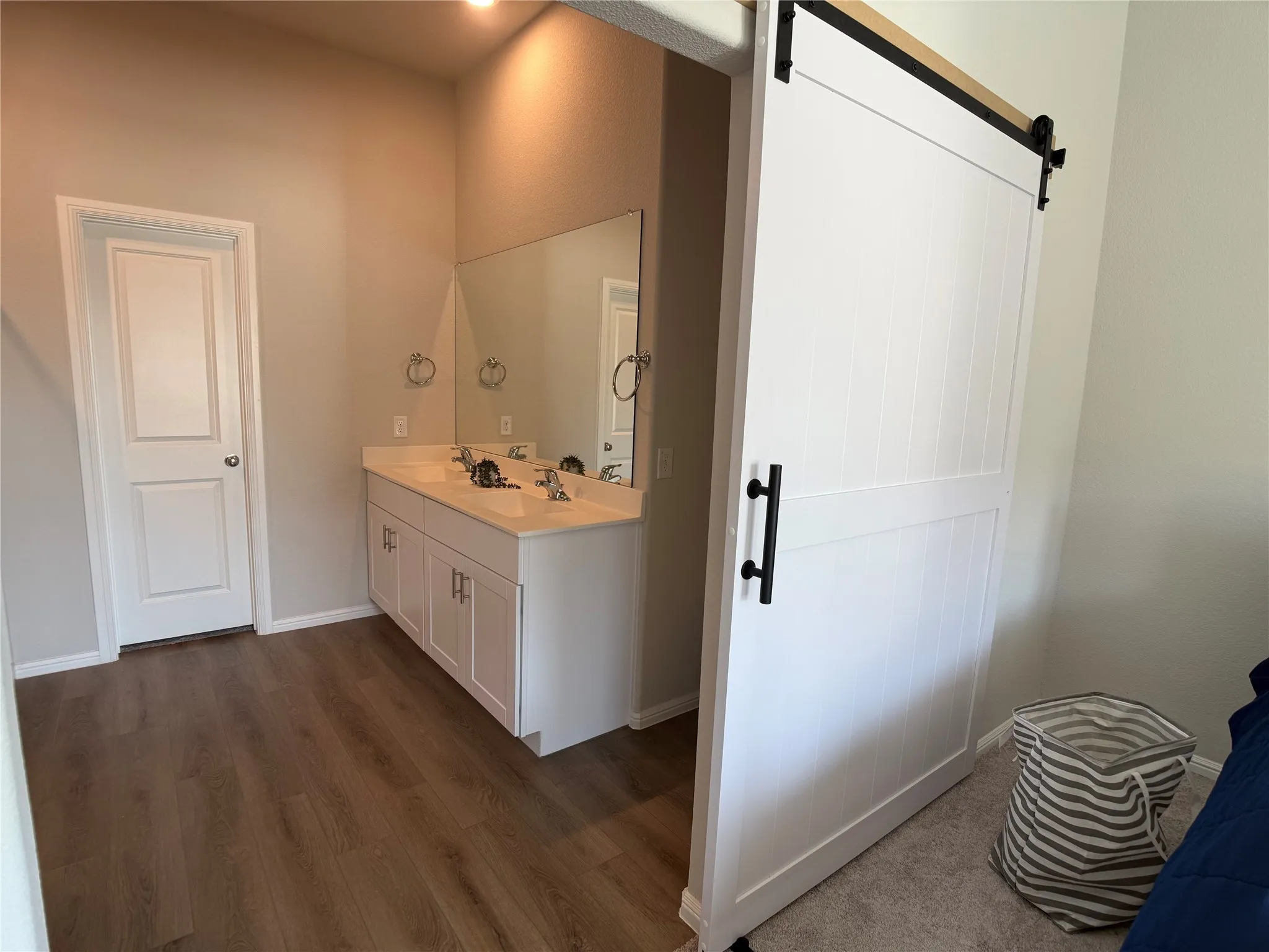 Full bath featuring double vanity and dark wood-style floors