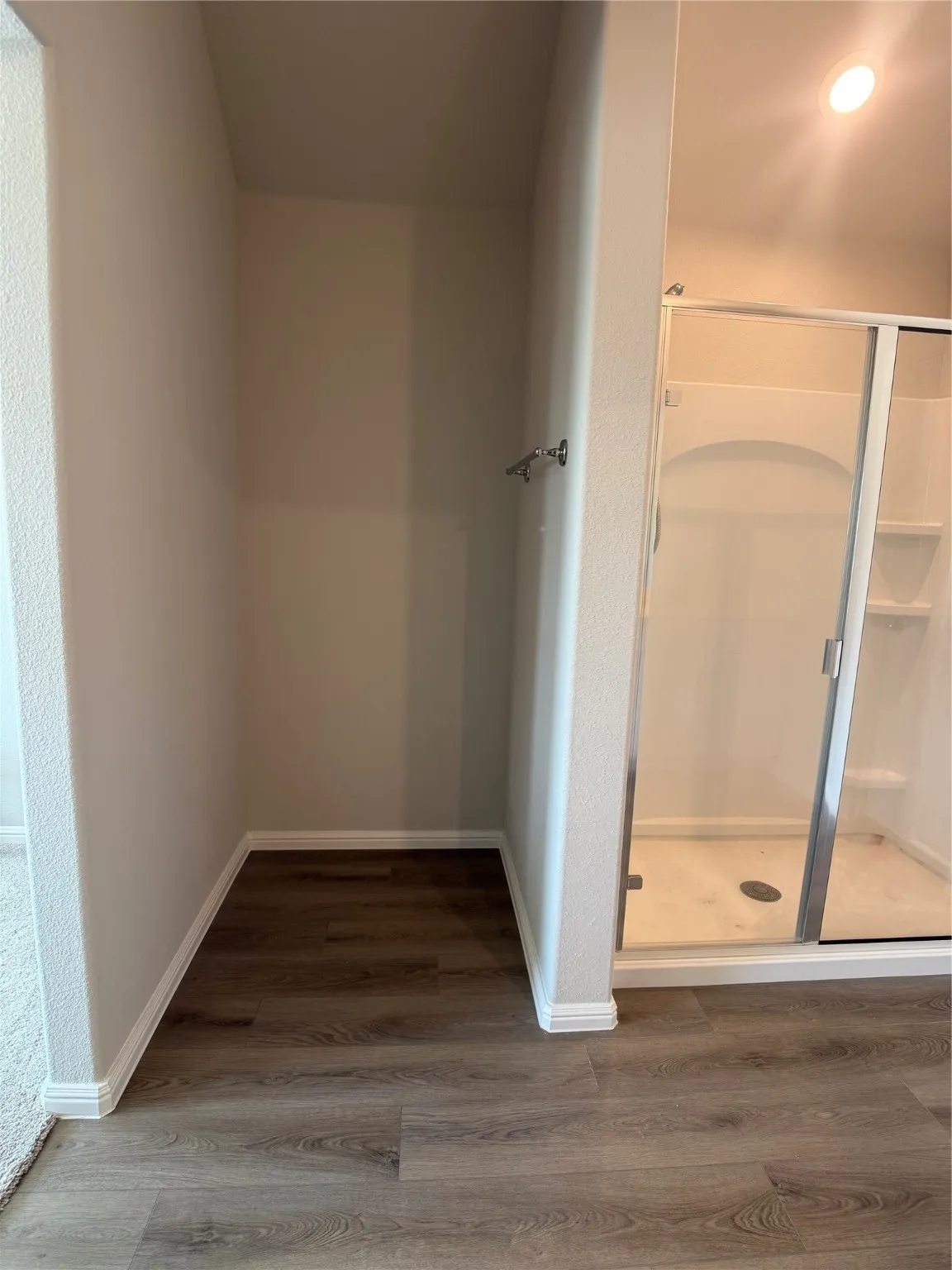 Bathroom featuring dark wood-style flooring and a shower stall