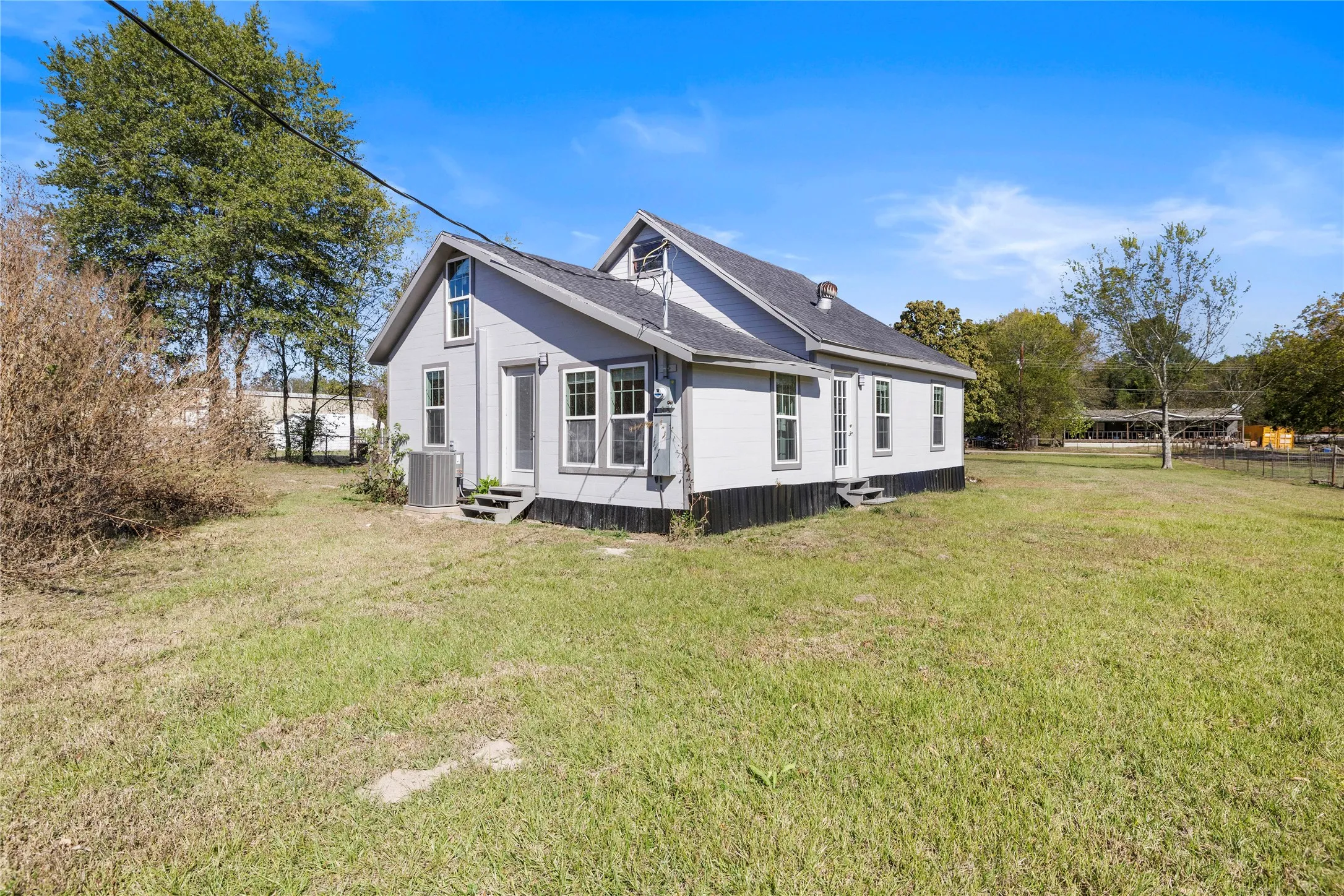 View of side of home with entry steps, a lawn, and a shingled roof