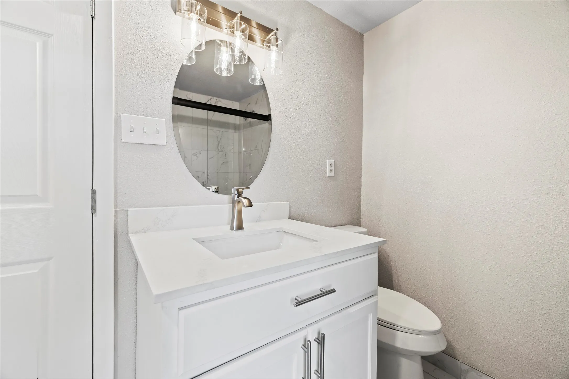 Bathroom featuring a textured wall, a stall shower, and vanity