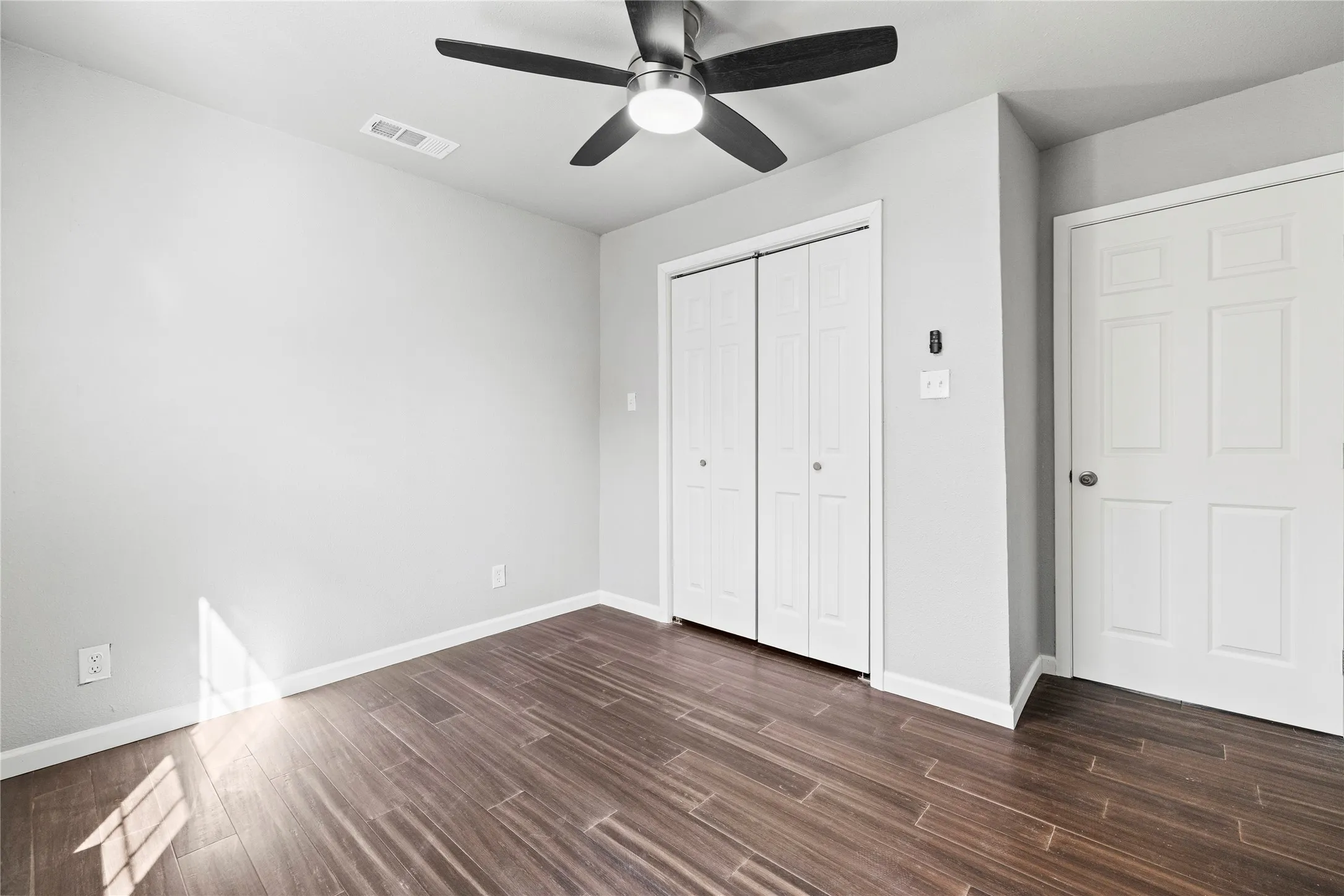  bedroom with dark wood finished floors, a ceiling fan, and a closet