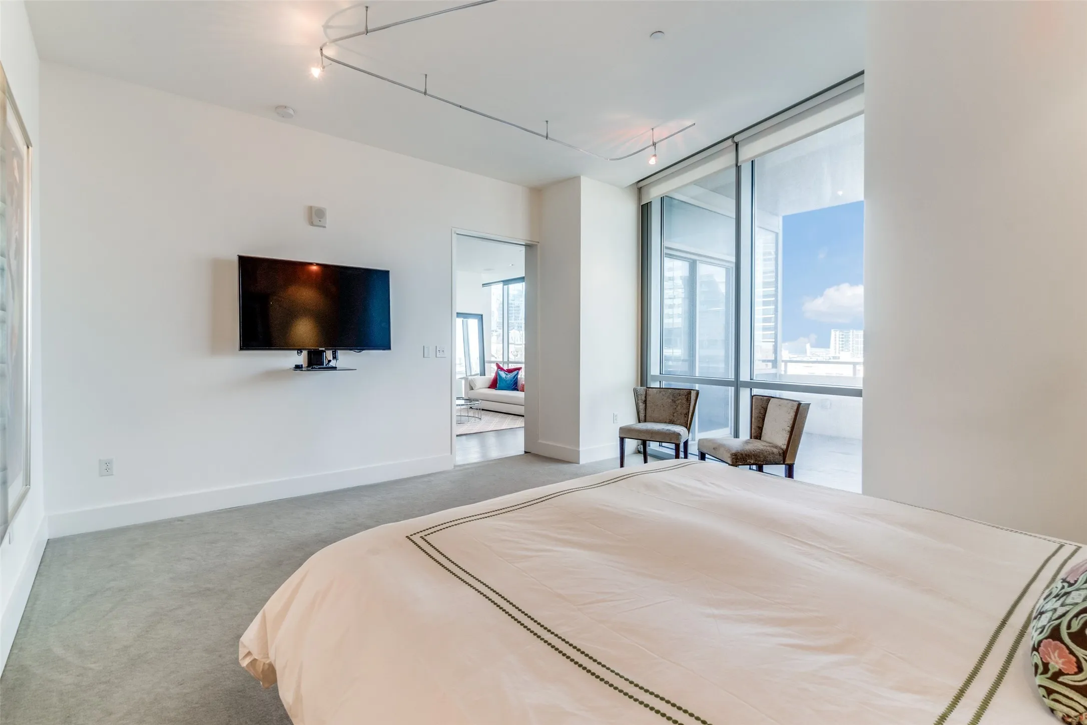 Bedroom with carpet flooring, rail lighting, and floor to ceiling windows