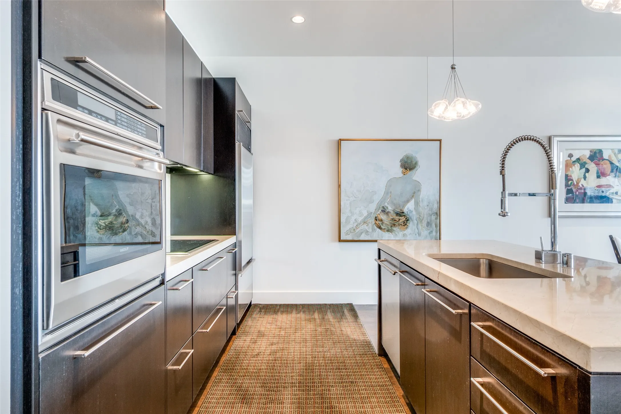 Kitchen featuring hanging light fixtures, stainless steel appliances, light stone countertops, recessed lighting, and modern cabinets