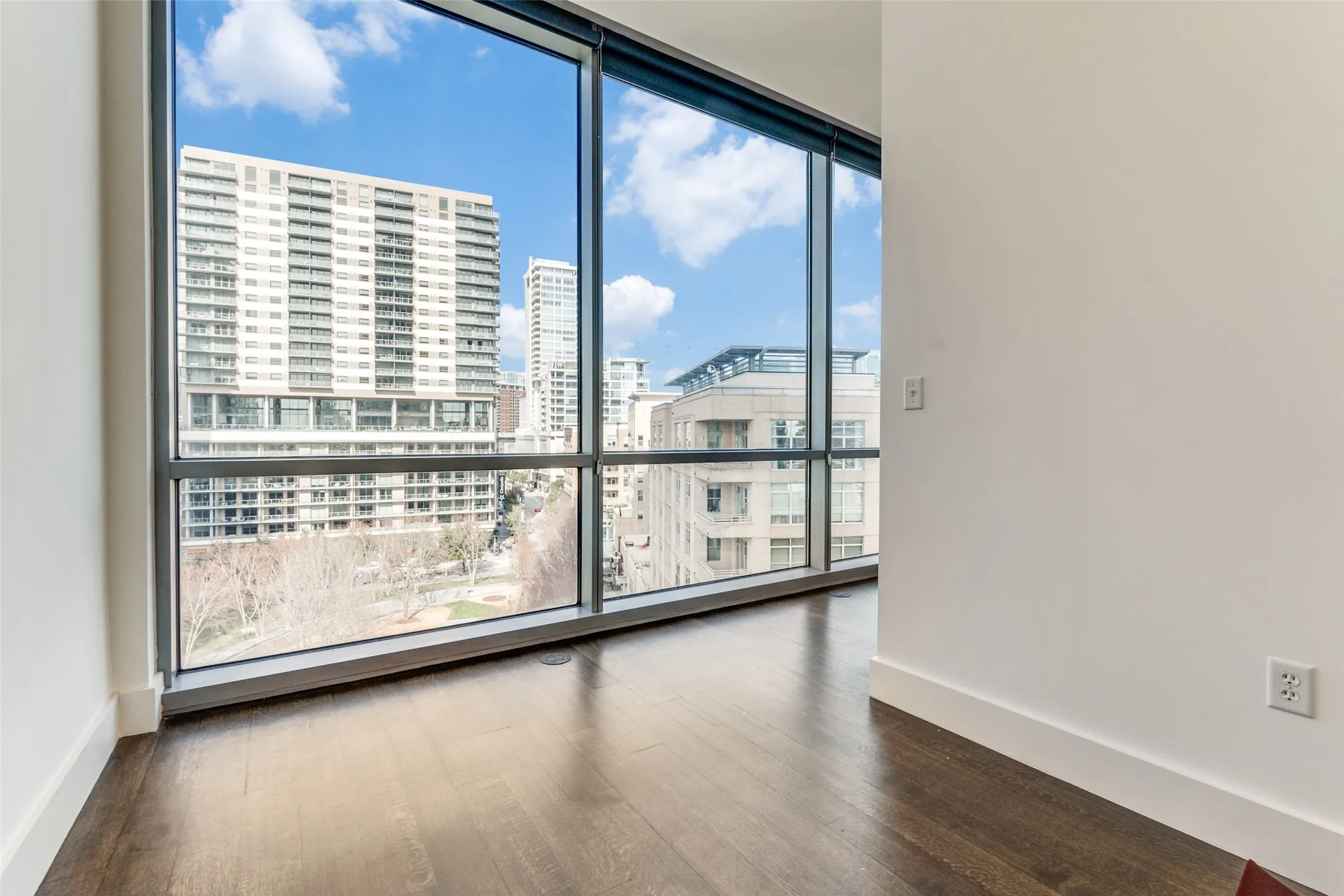 Spare room featuring dark wood-type flooring, a city view, and expansive windows