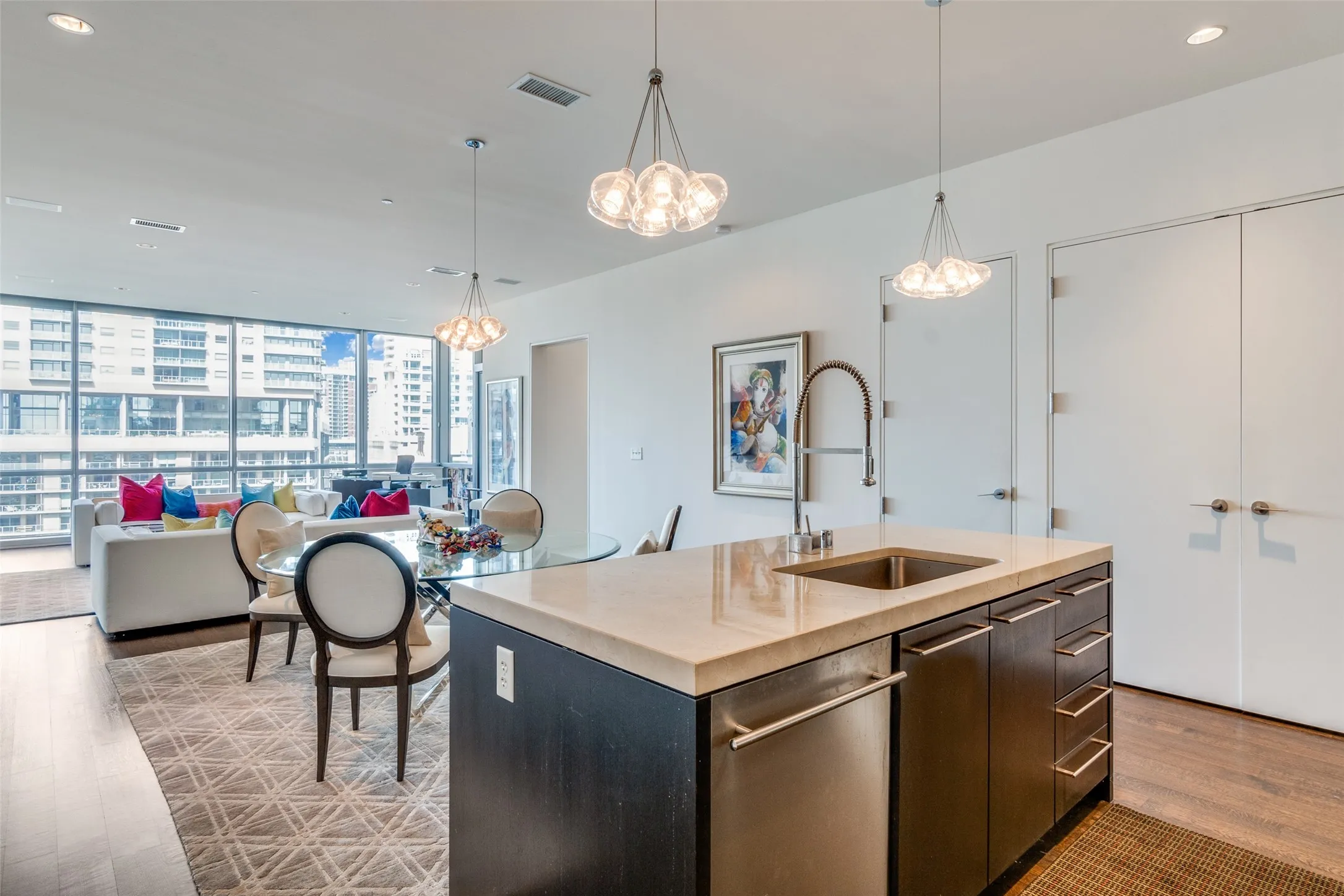 Kitchen with recessed lighting, pendant lighting, light wood finished floors, a wall of windows, and a kitchen island with sink
