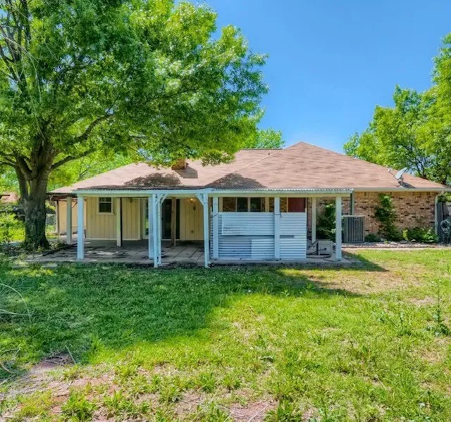 Back of property featuring a yard, board and batten siding, a patio, and a chimney