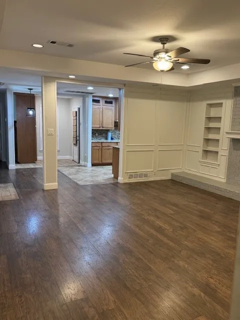 Unfurnished living room featuring a ceiling fan, recessed lighting, built in shelves, and dark wood-style flooring