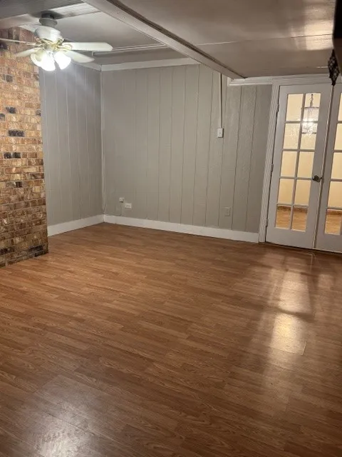 Empty room with wood finished floors, wood walls, and a ceiling fan